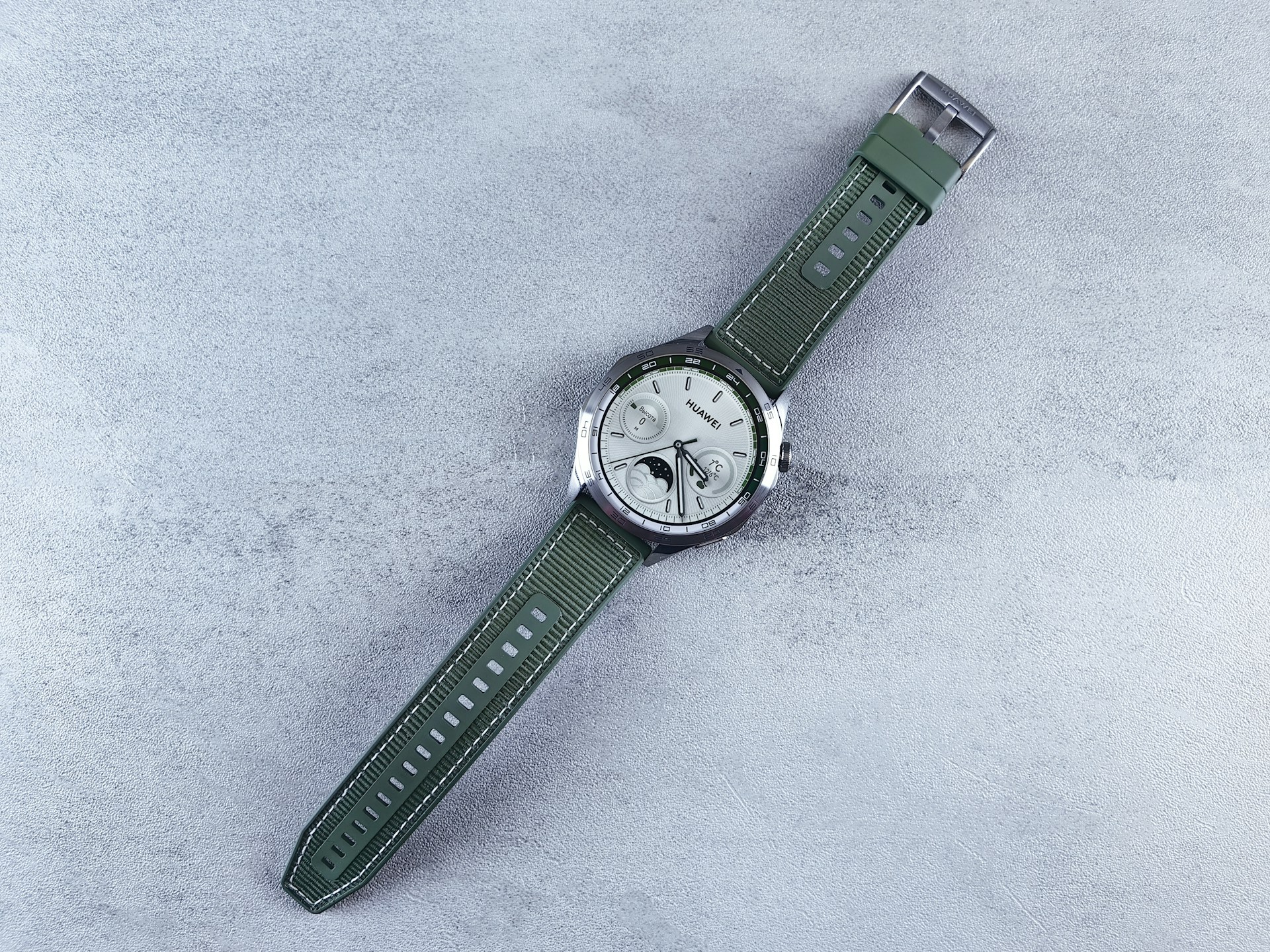 A wristwatch with a green strap on a textured surface.