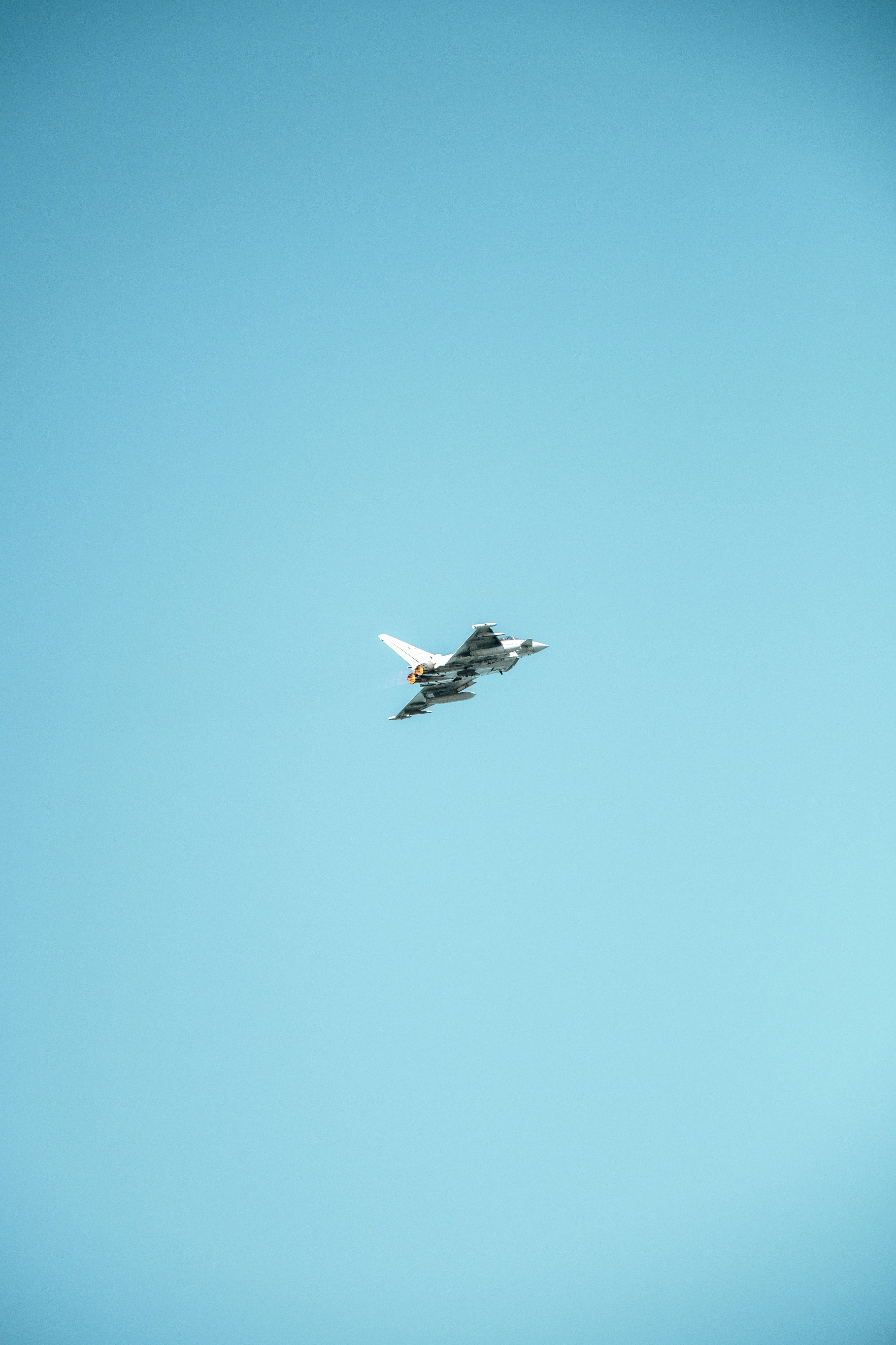 A fighter jet flies high in the clear blue sky.