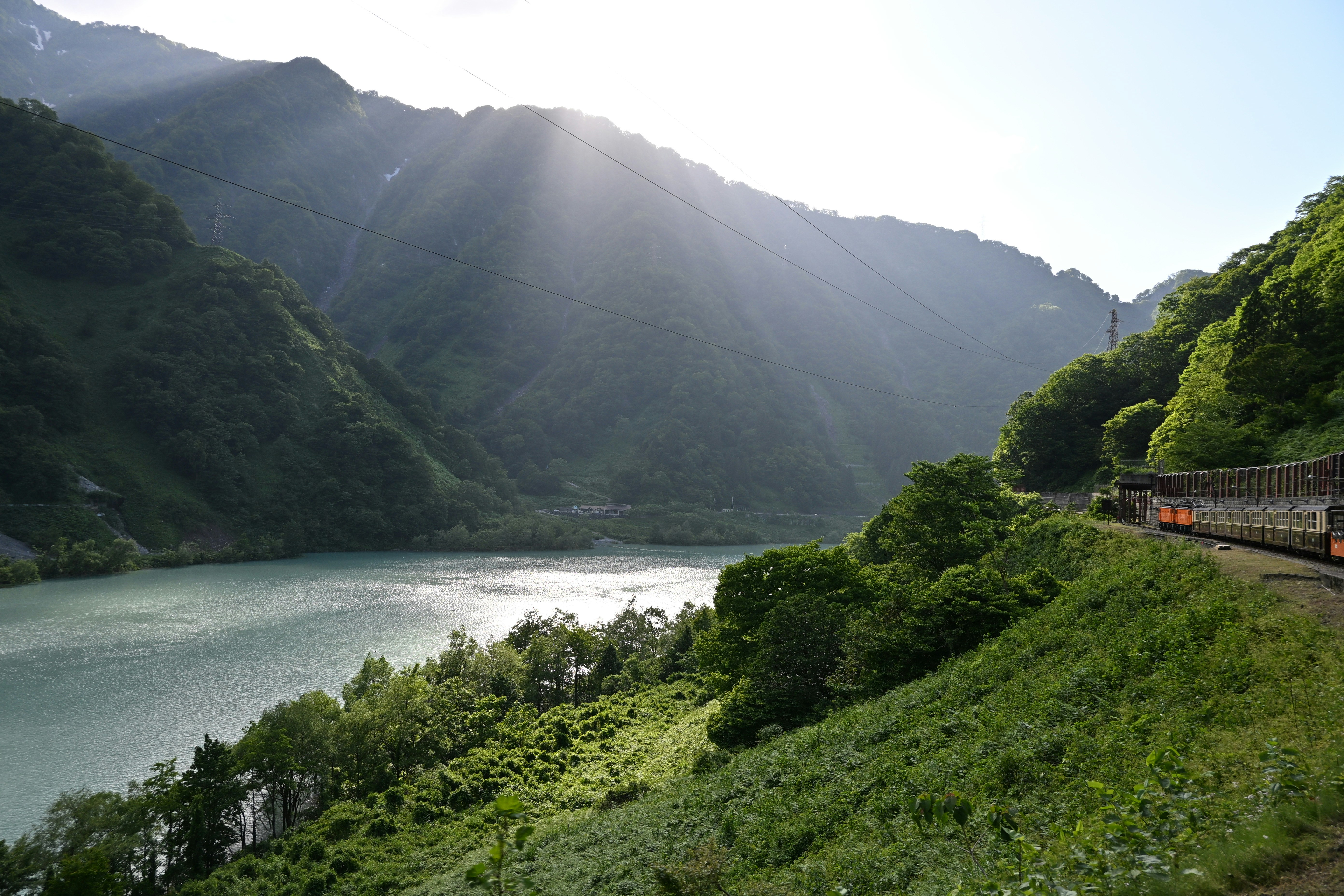 Train travels alongside a serene mountain lake.