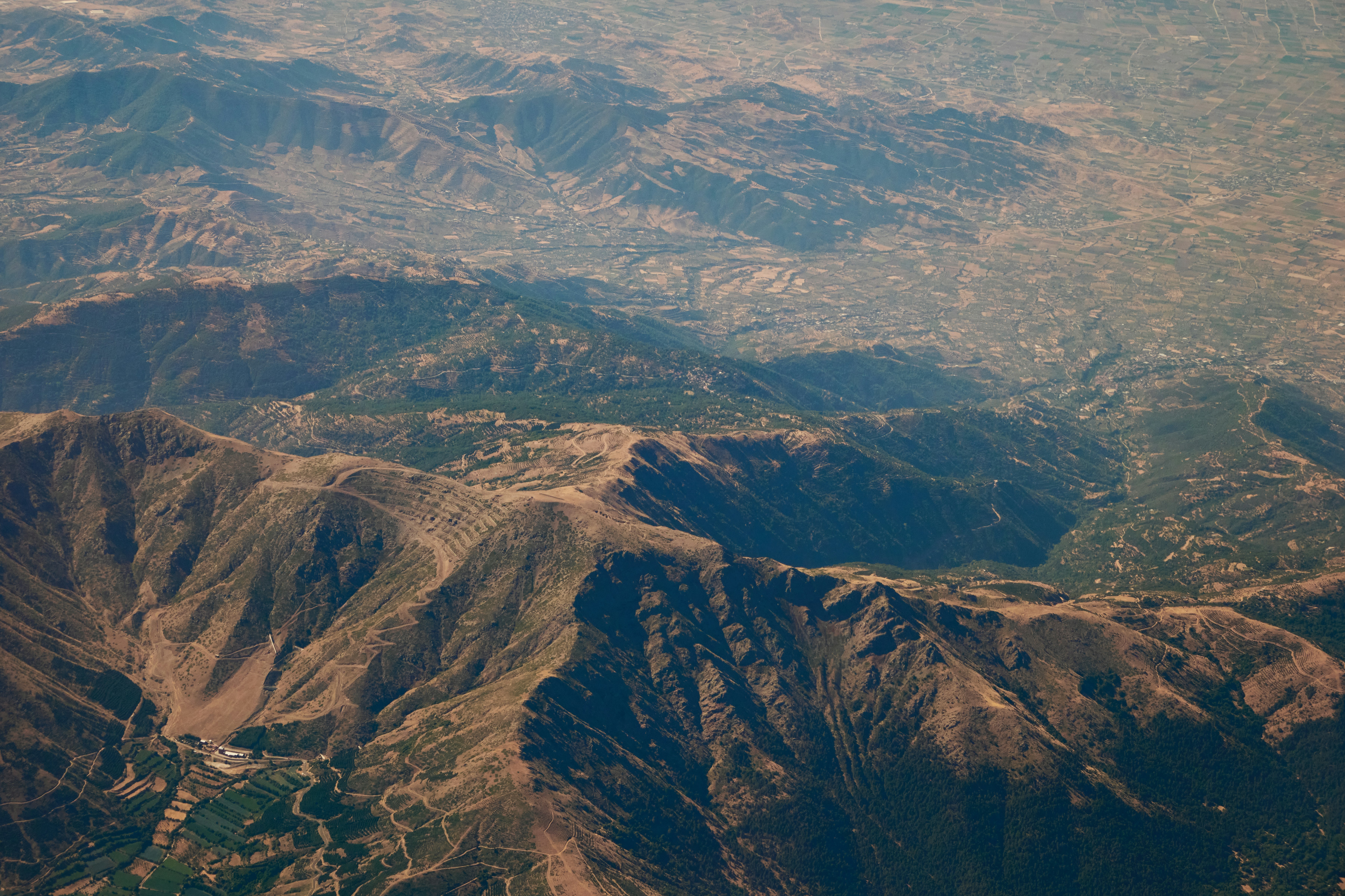 Aerial view of rugged mountain ranges with sparse vegetation.