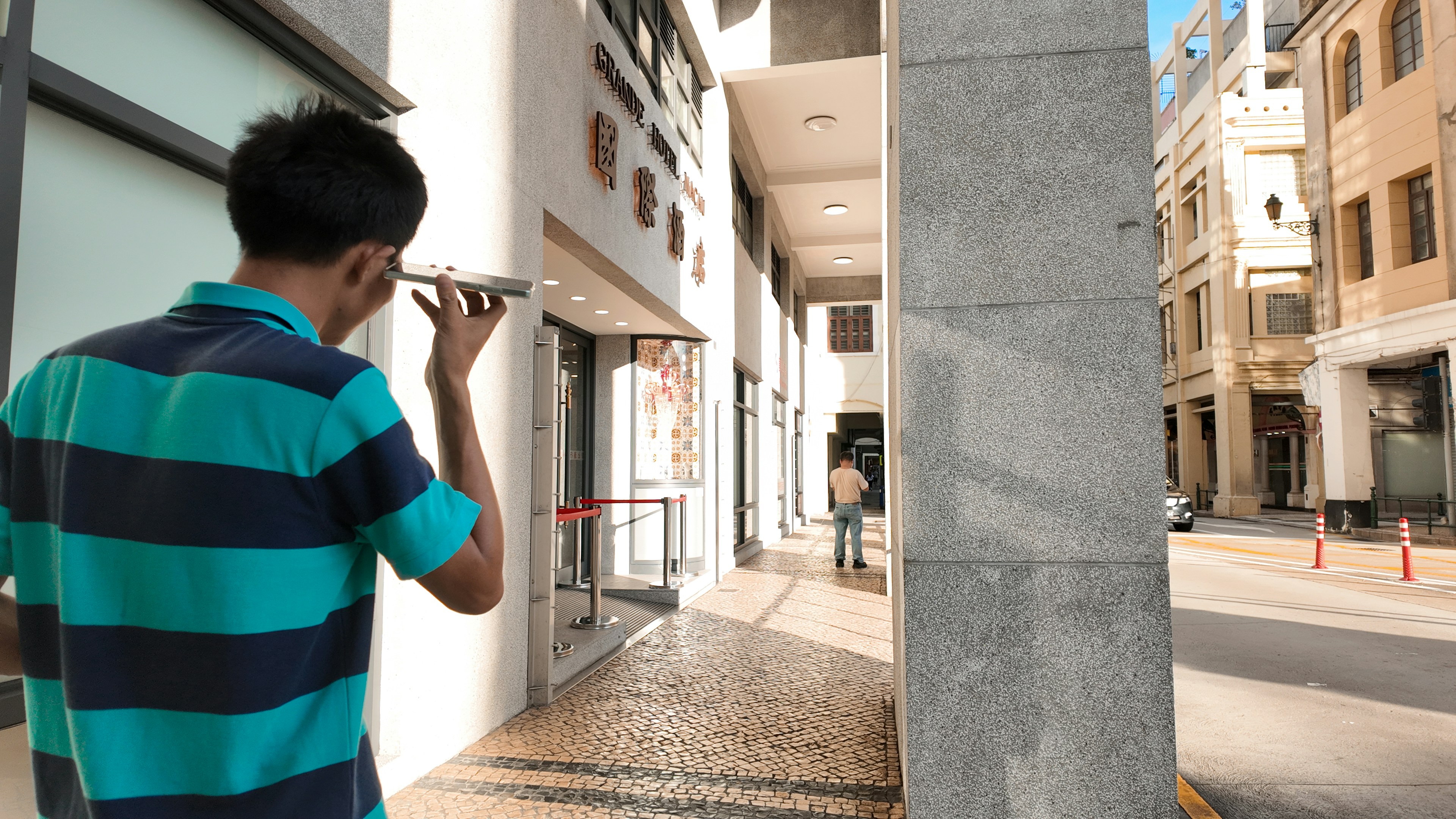 Man looking at phone in a sunlit walkway
