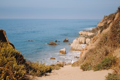 Sandy path leading to a rocky beach and ocean.