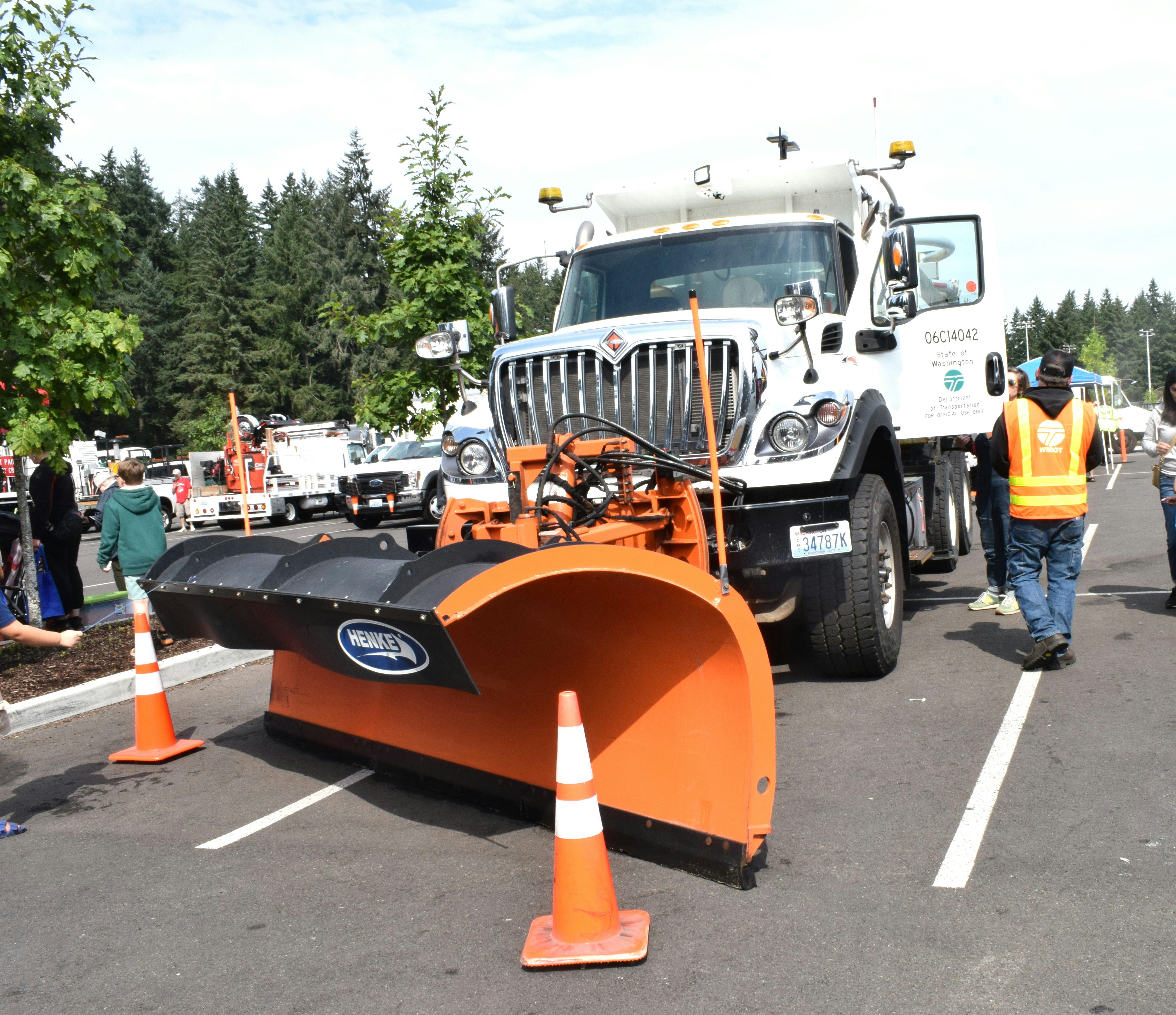 A large white snow plow truck with an orange blade.