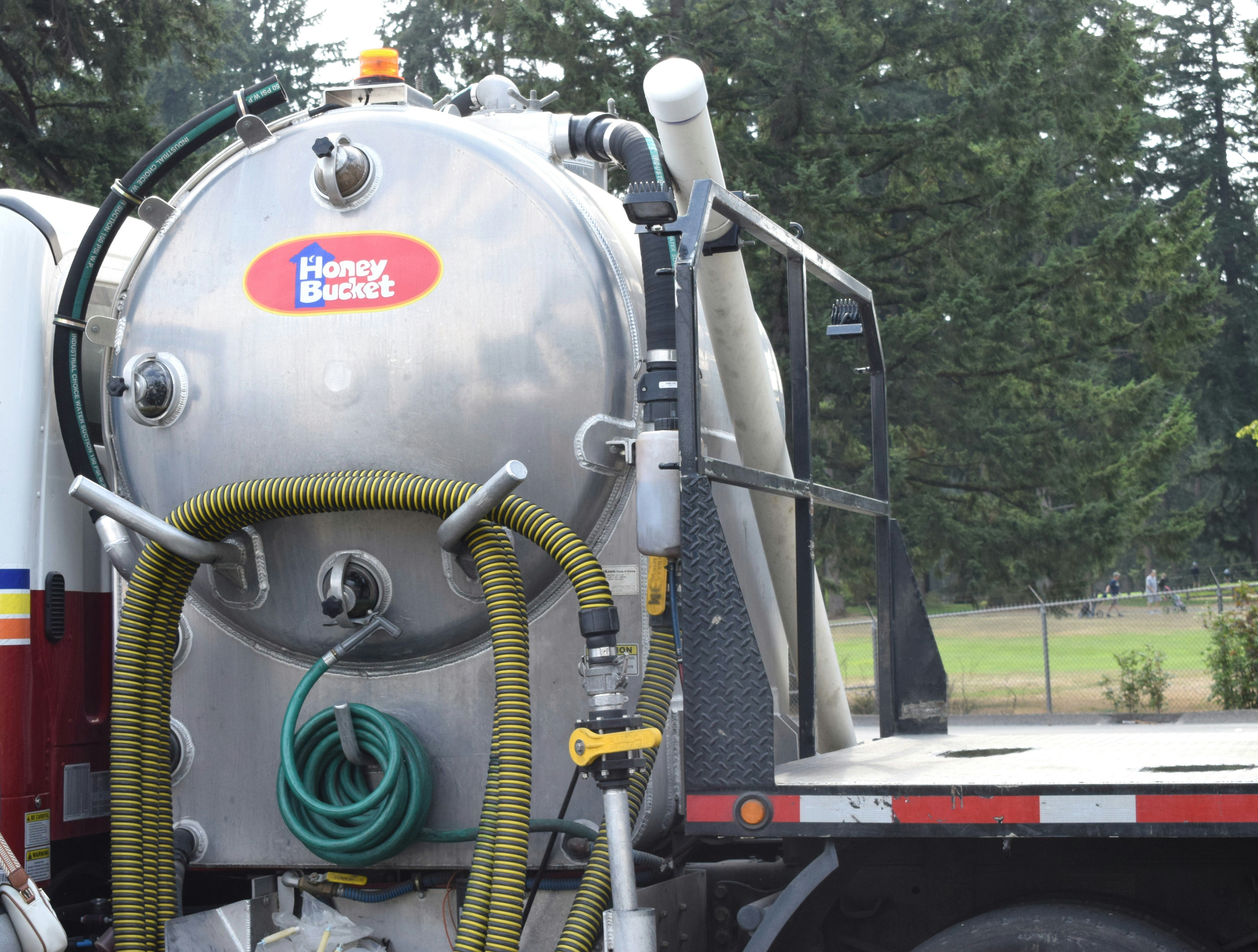 Silver vacuum truck tank with hoses and pipes