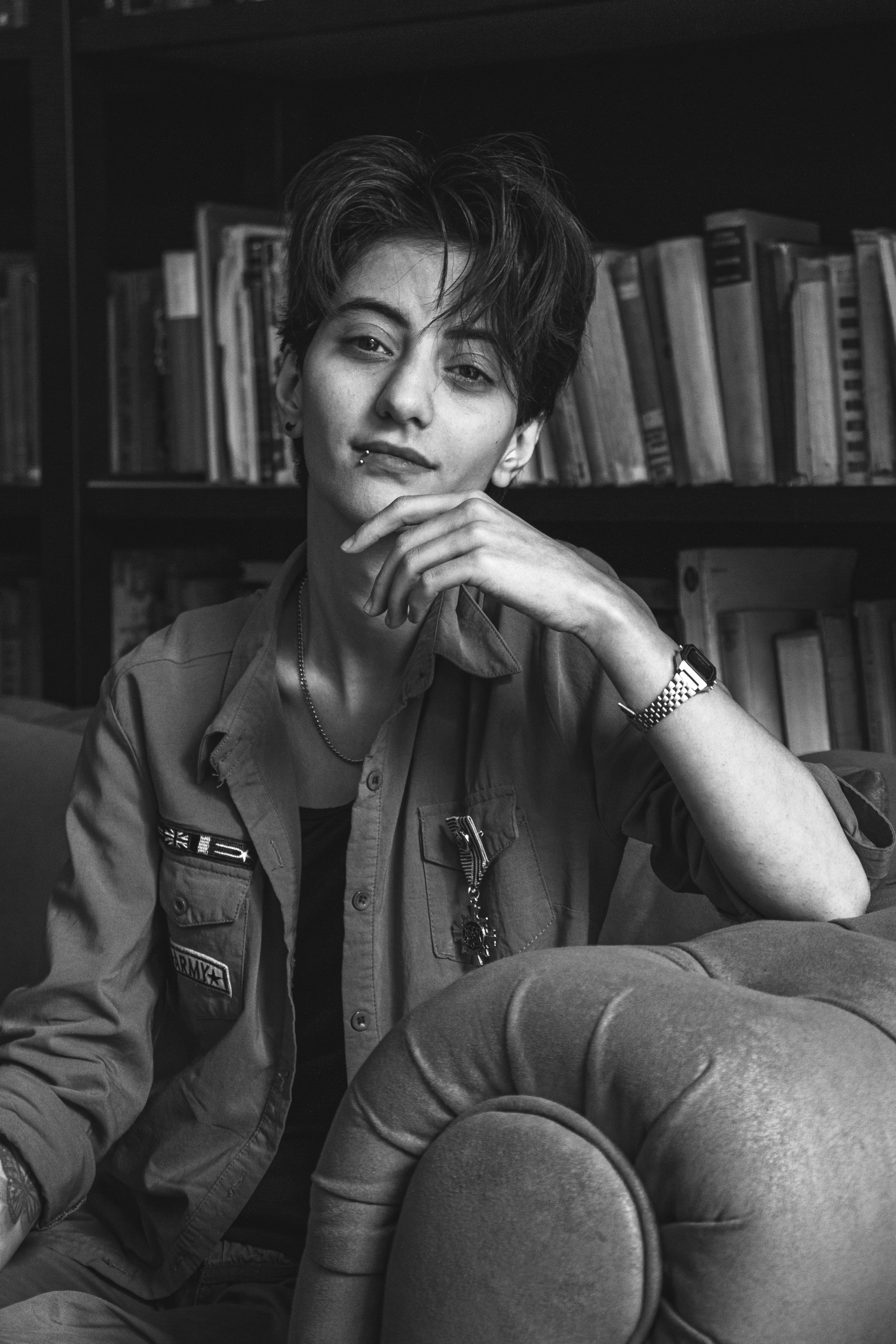 A person sits on a couch in front of bookshelves.