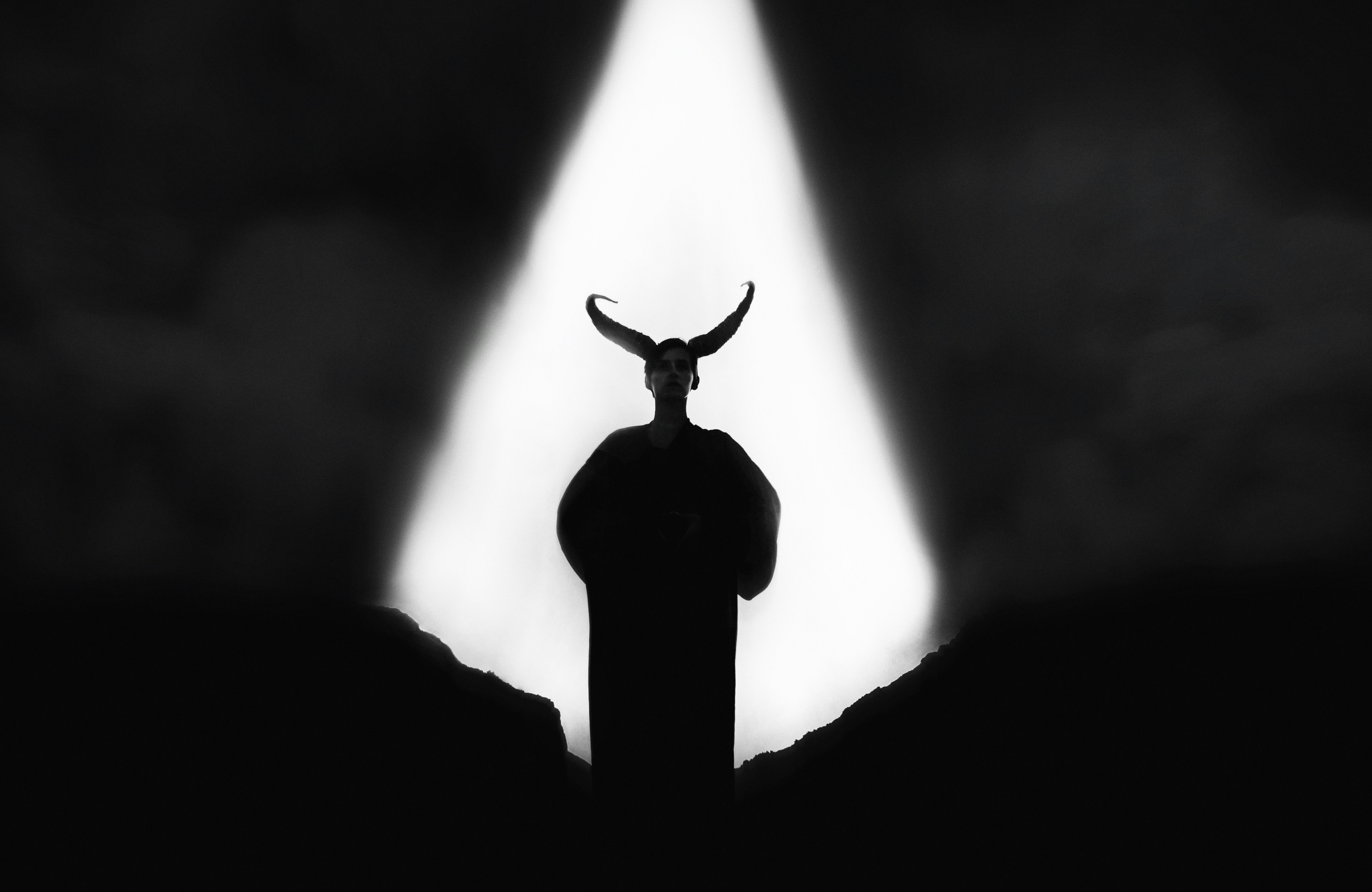 Silhouette of a horned figure in dramatic spotlight
