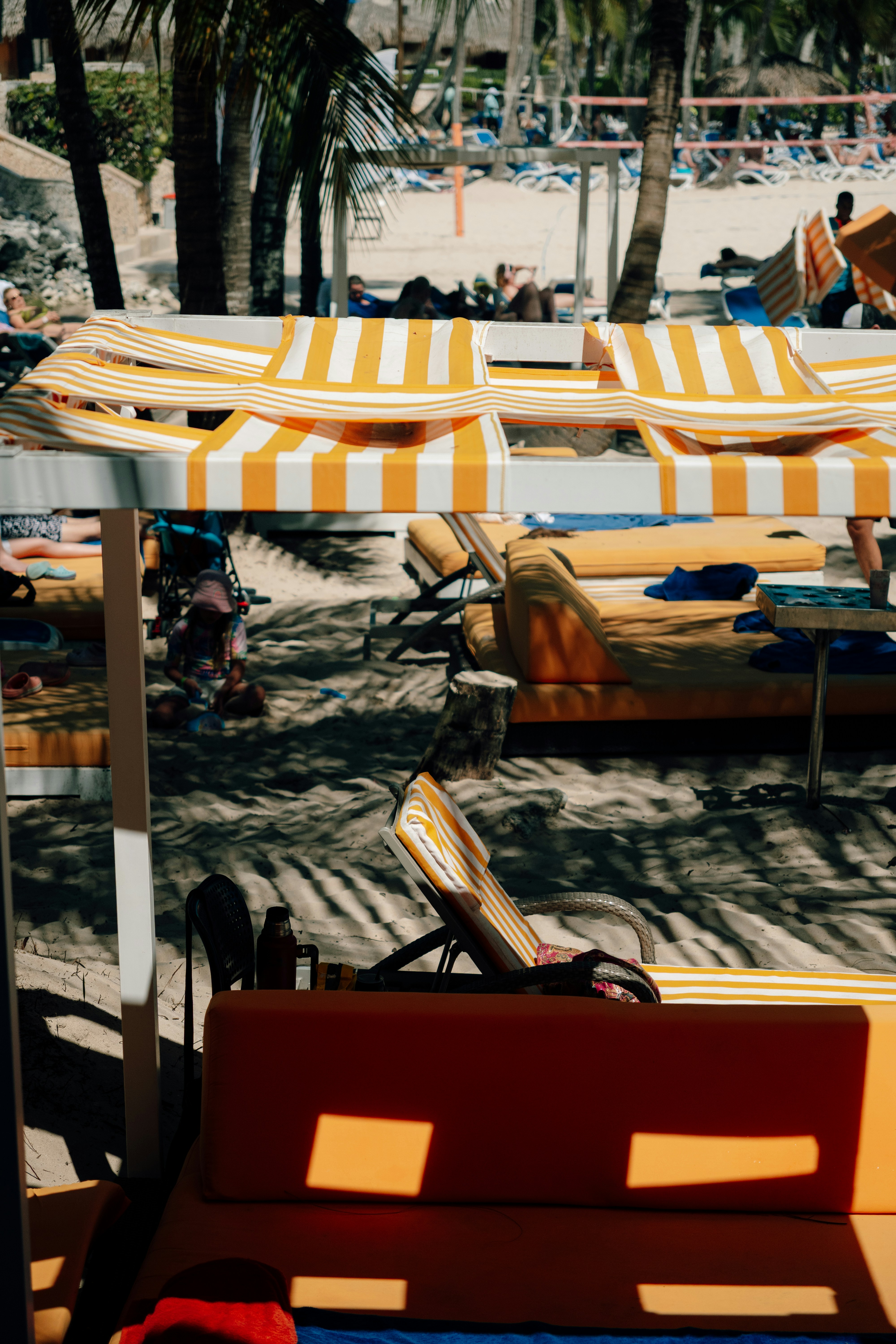 Orange and white striped lounge chairs on a sunny beach.