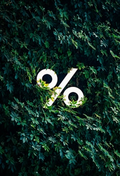 A white percentage sign logo surrounded by green leaves.