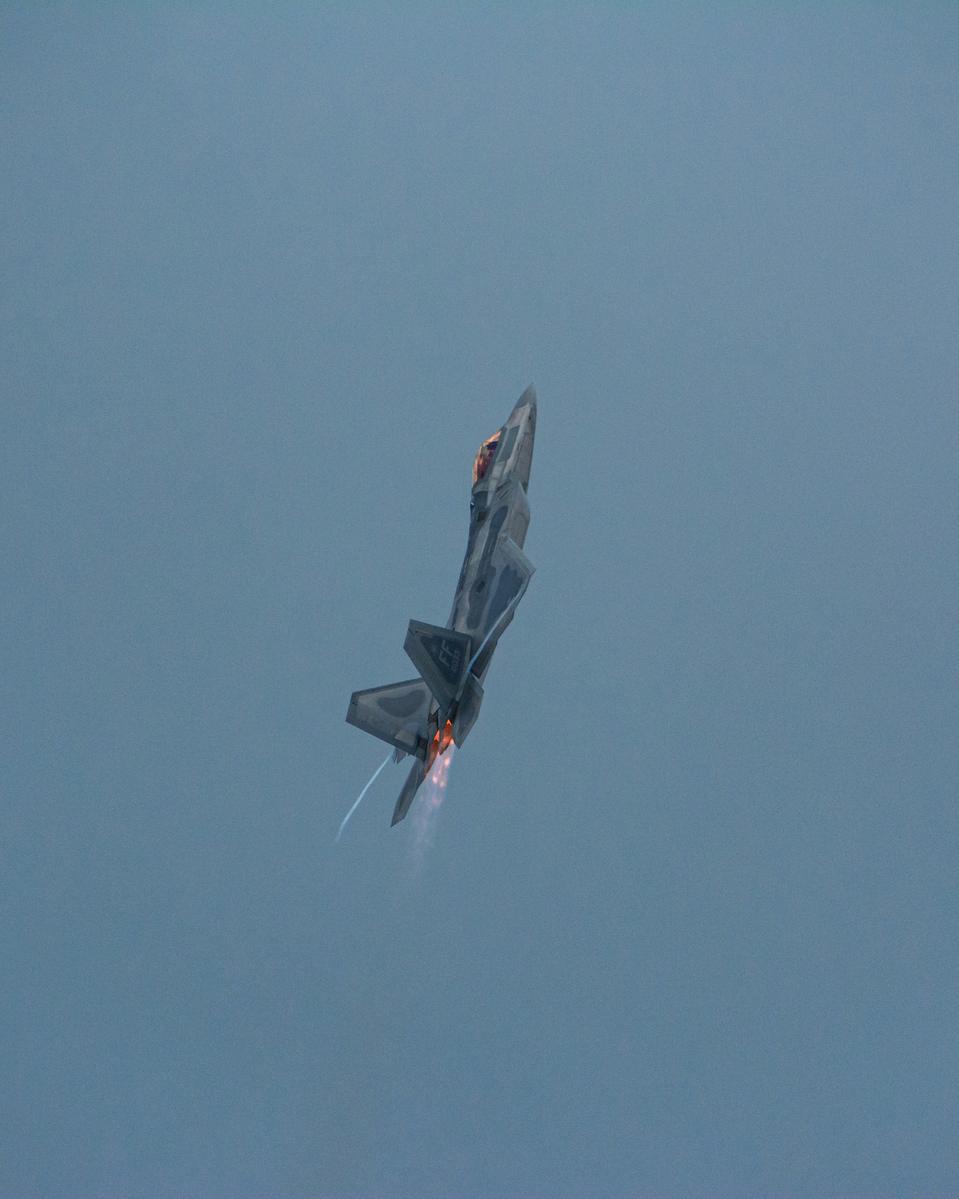 Fighter jet performing an aerial maneuver with afterburners engaged