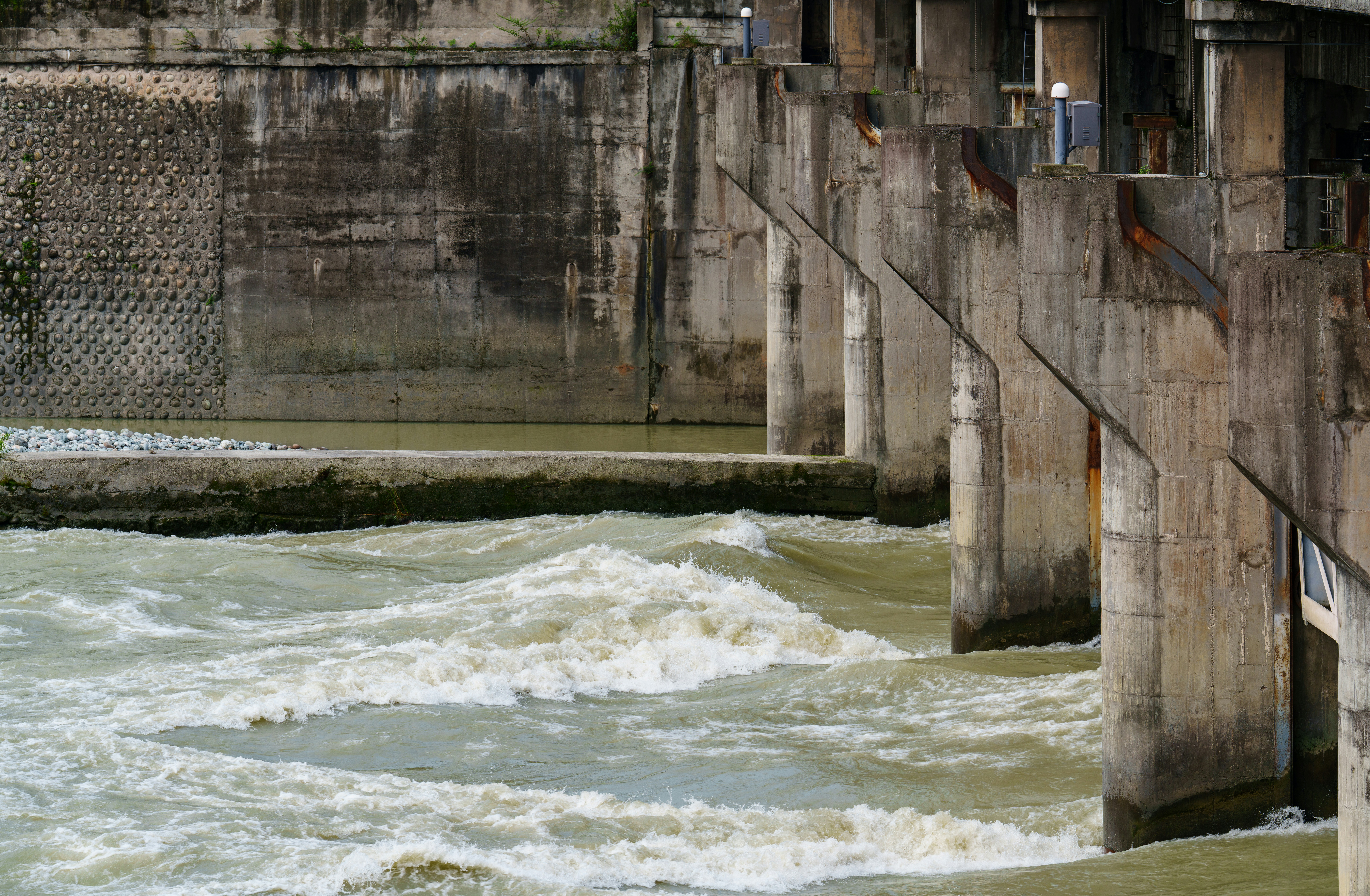Rough water flows past concrete structures.
