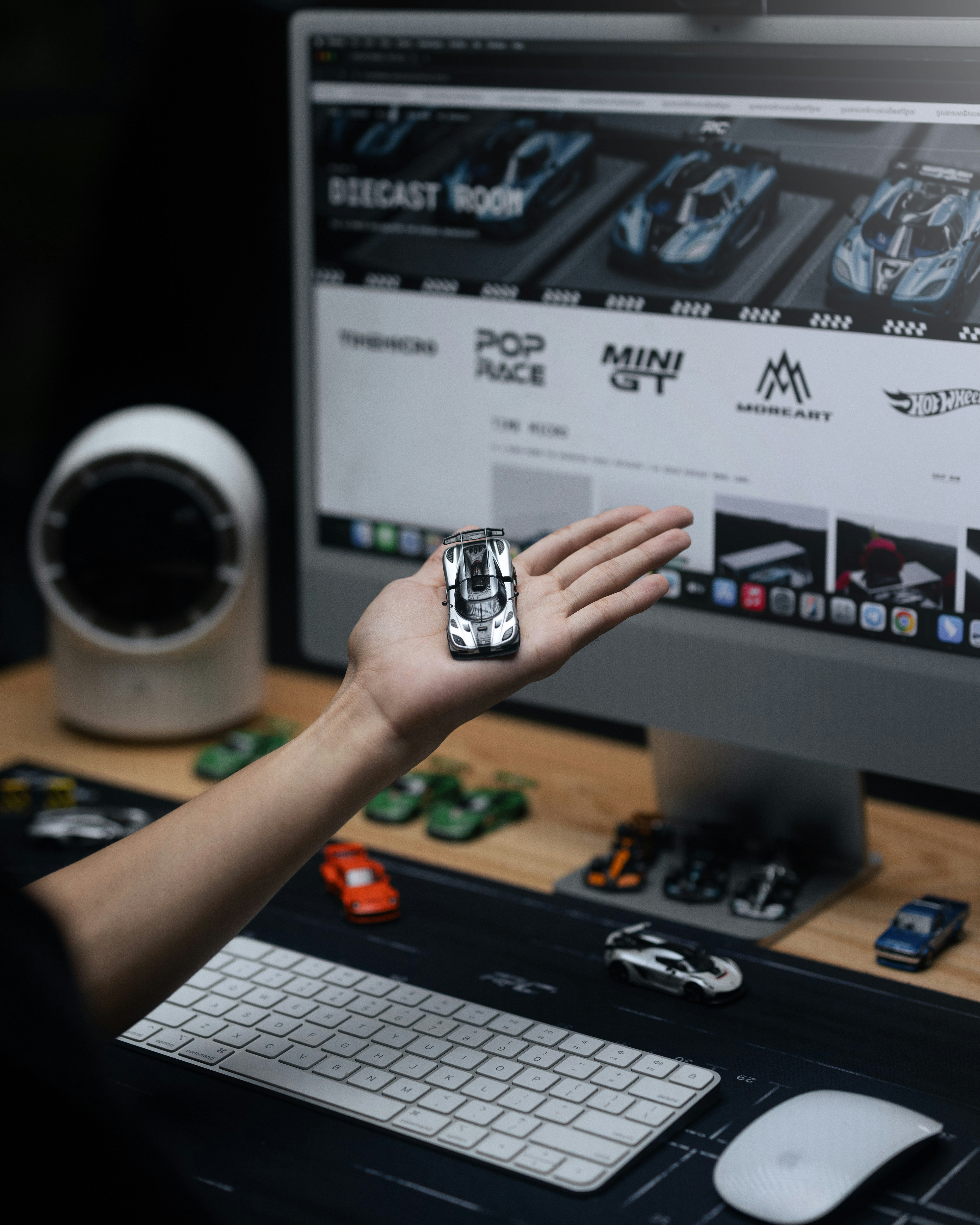 Person holding a miniature car in front of a computer