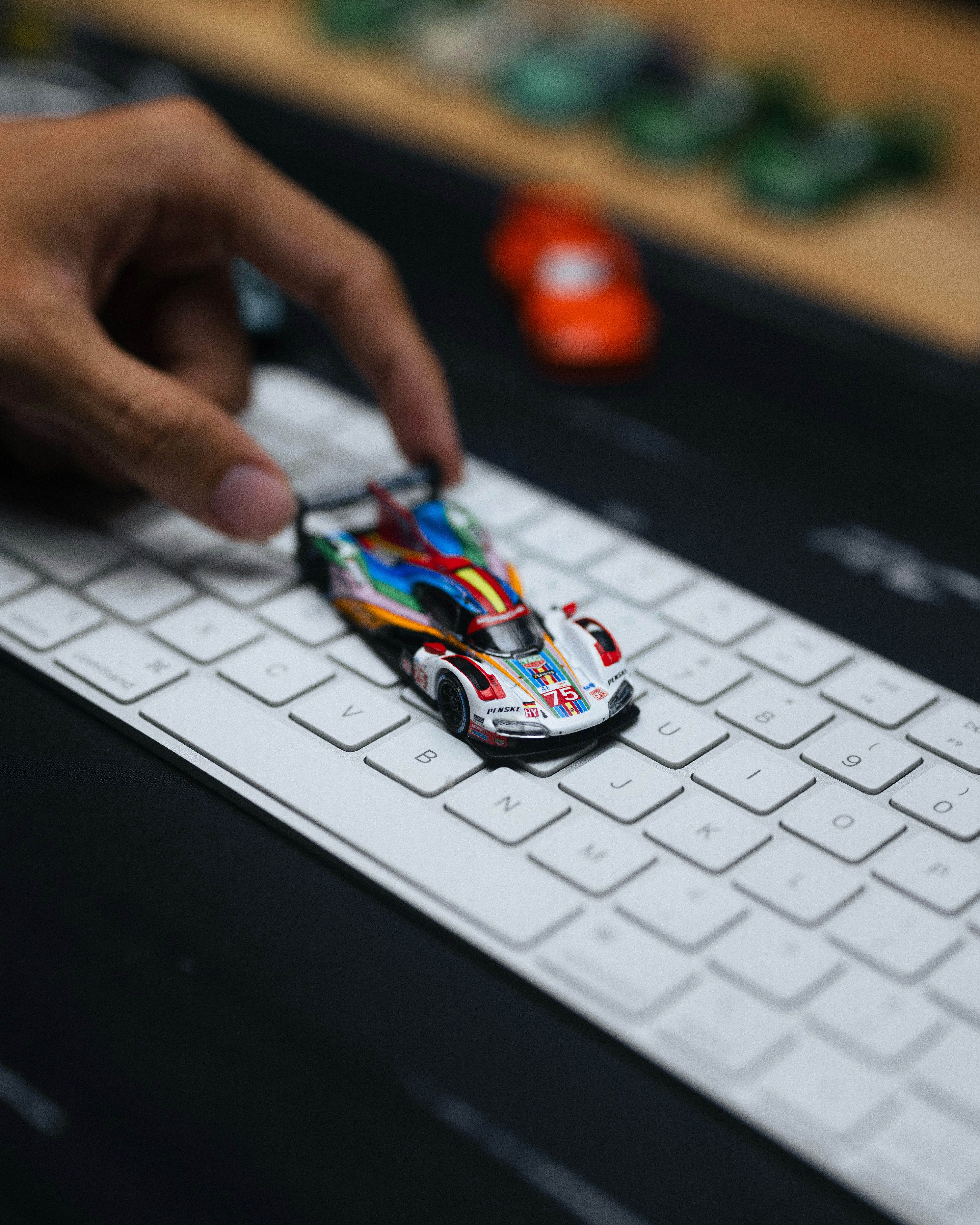 Hand placing a colorful toy race car on a keyboard