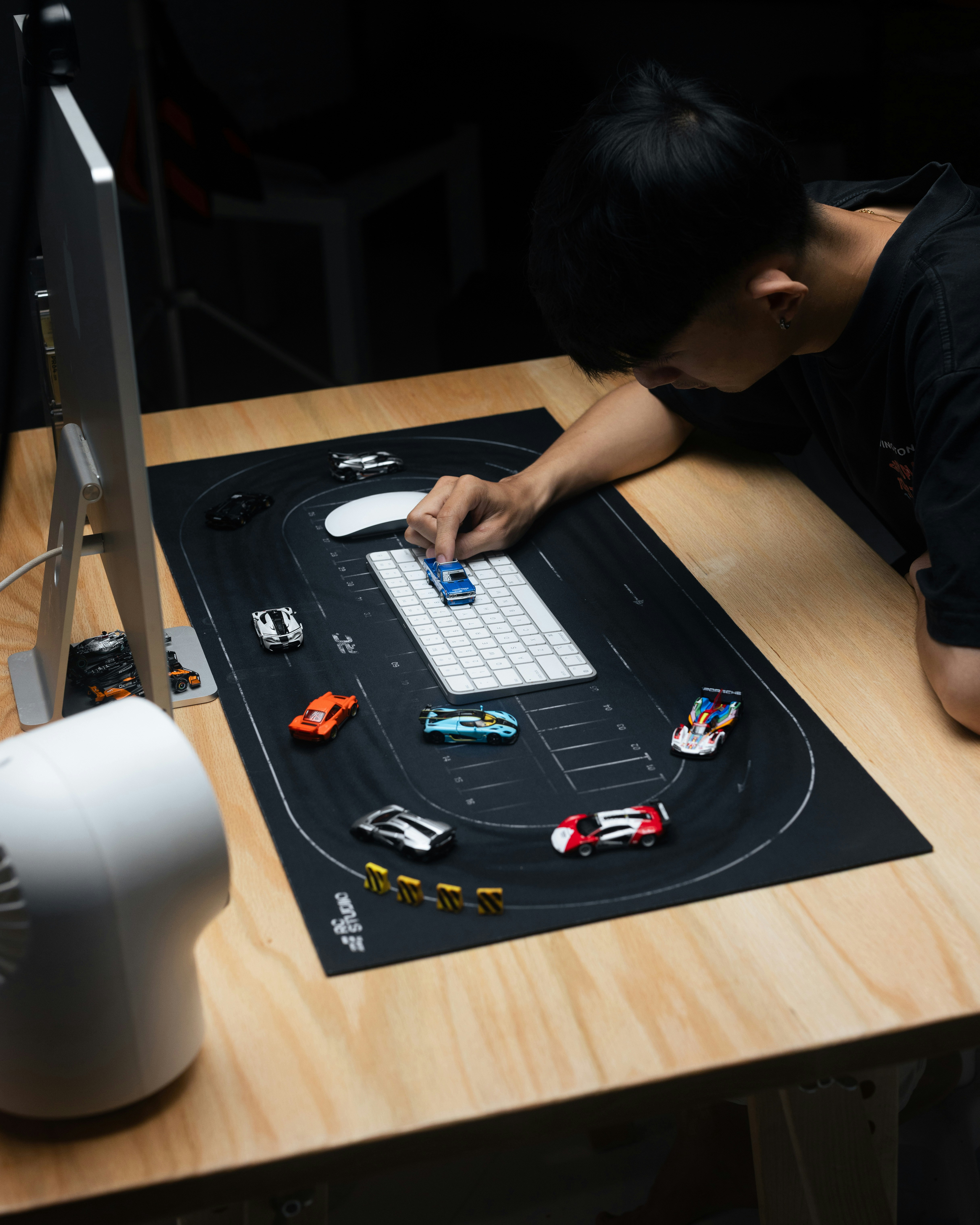 Man arranging toy cars on a race track mat.