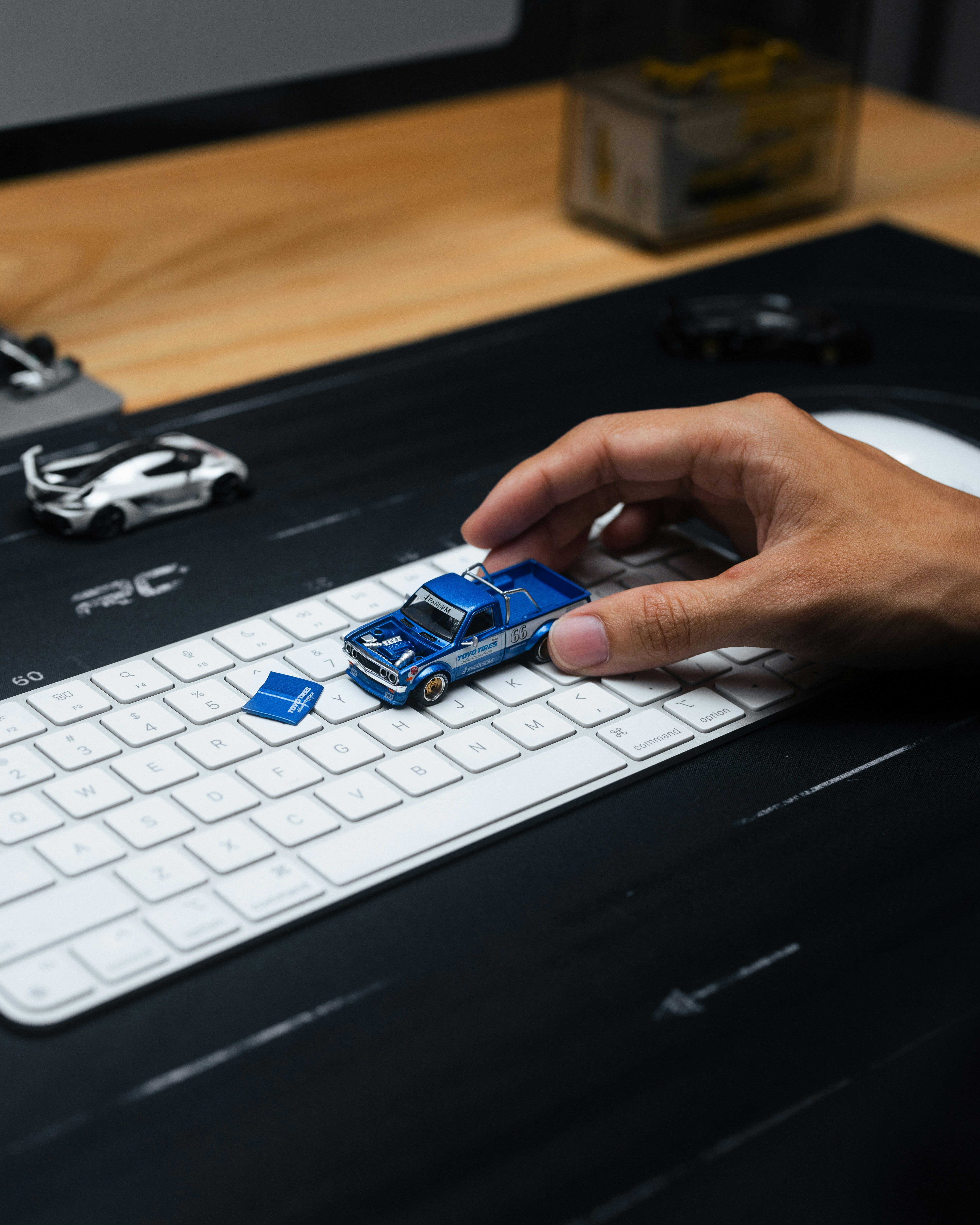 Hand placing a blue toy car on a keyboard.