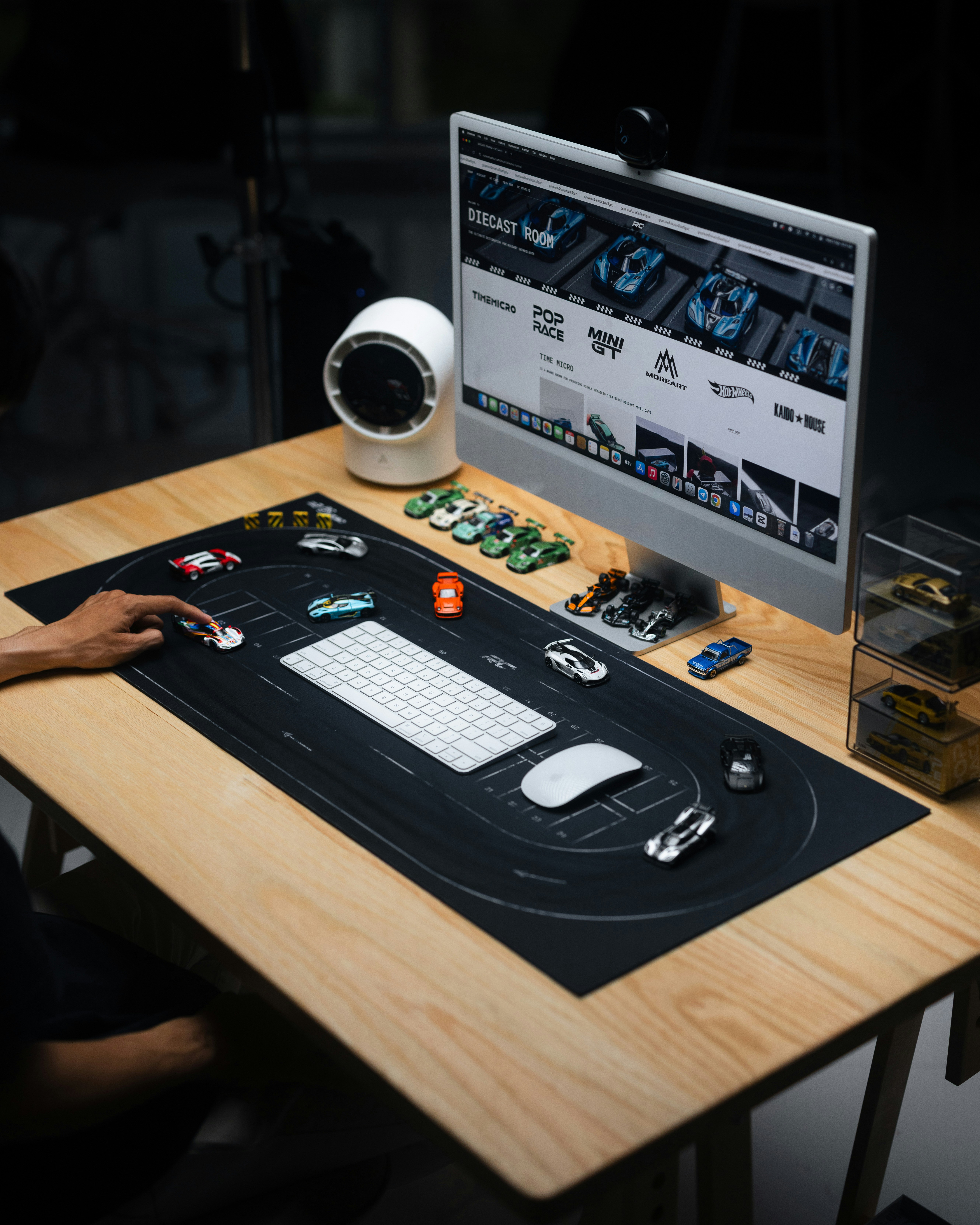 Desk setup with race track mousepad and toy cars.