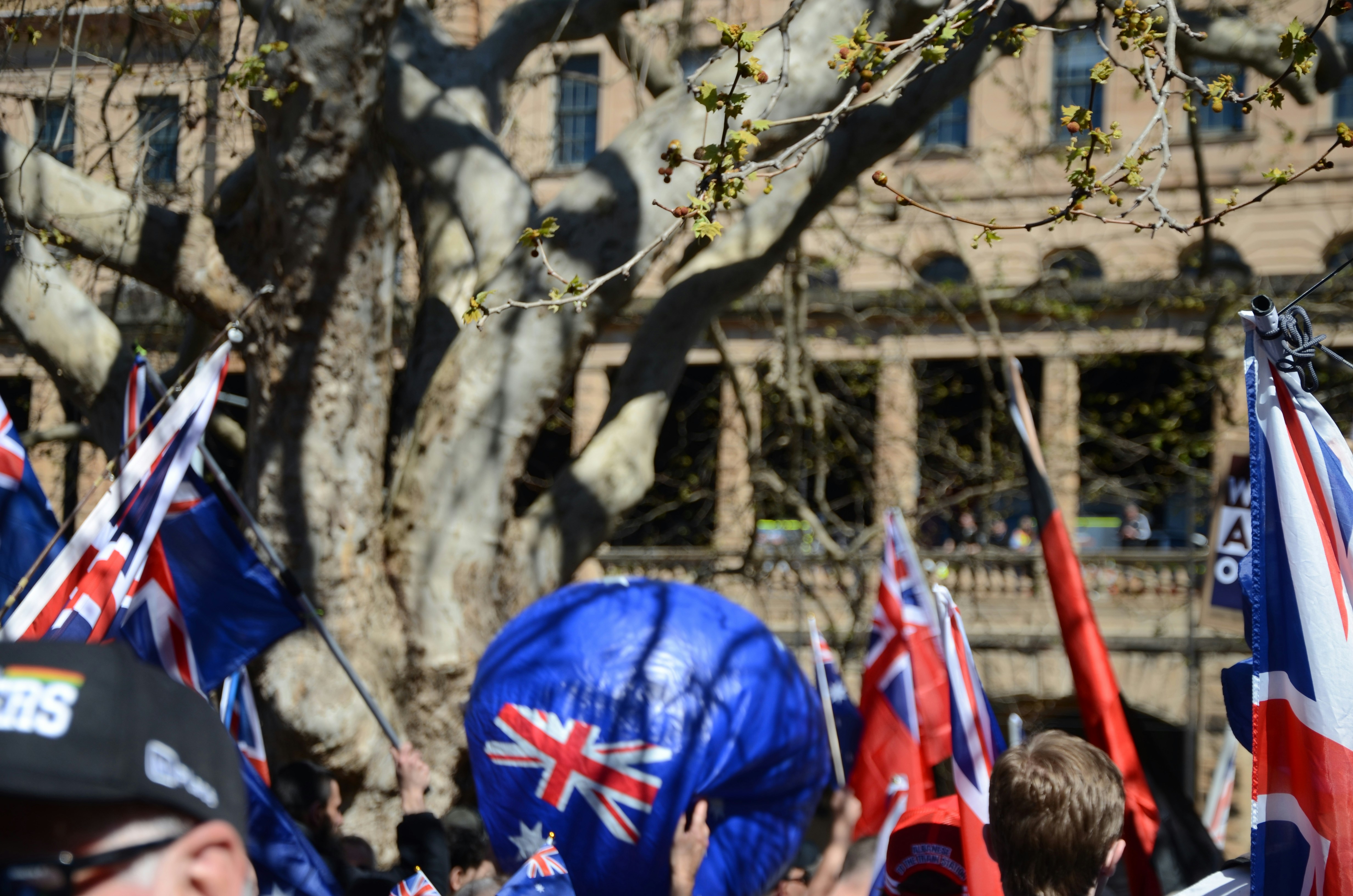 Crowd holding australian flags near building
