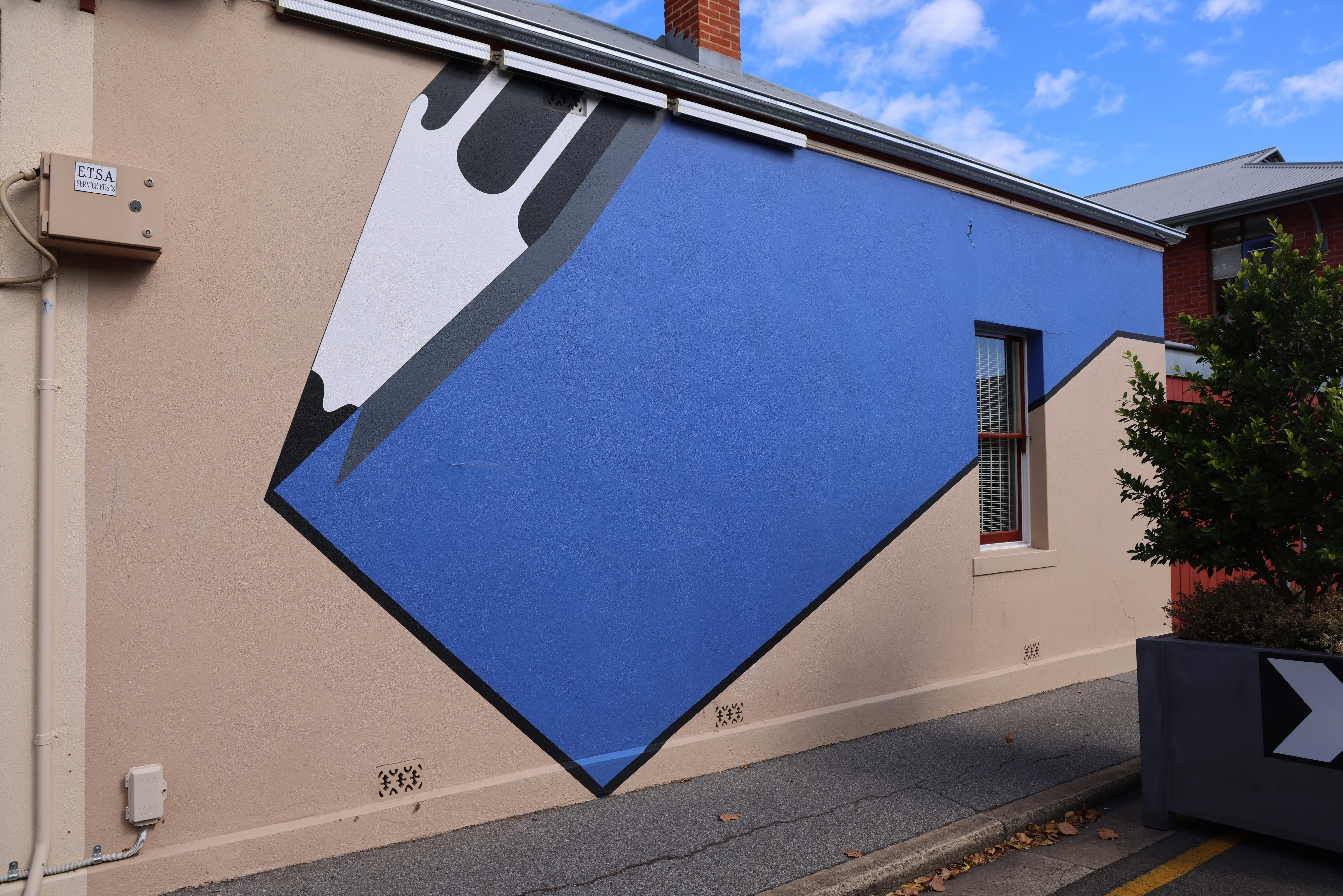 Abstract blue mural on a beige building wall.