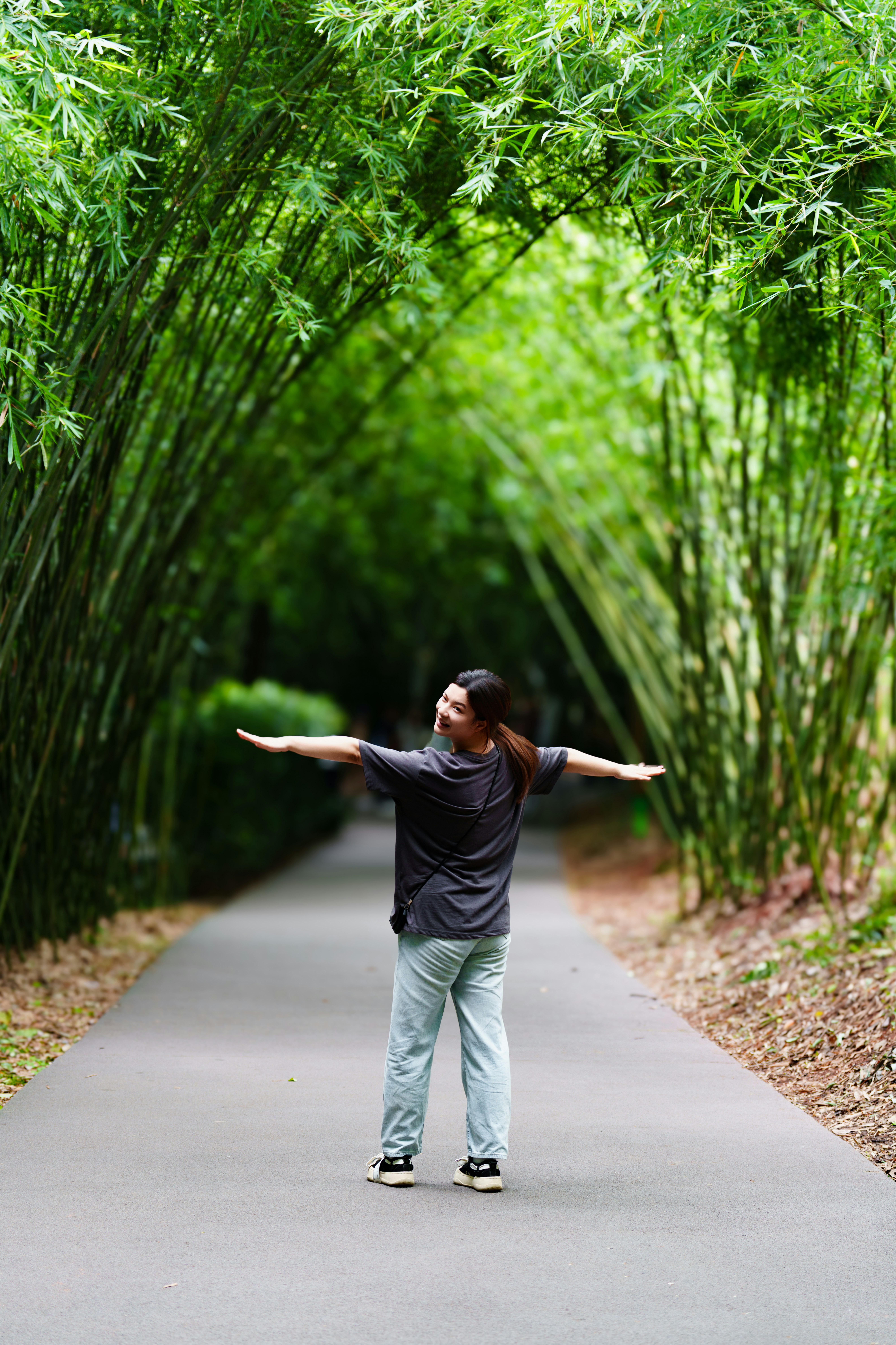 Person with arms outstretched in a bamboo tunnel