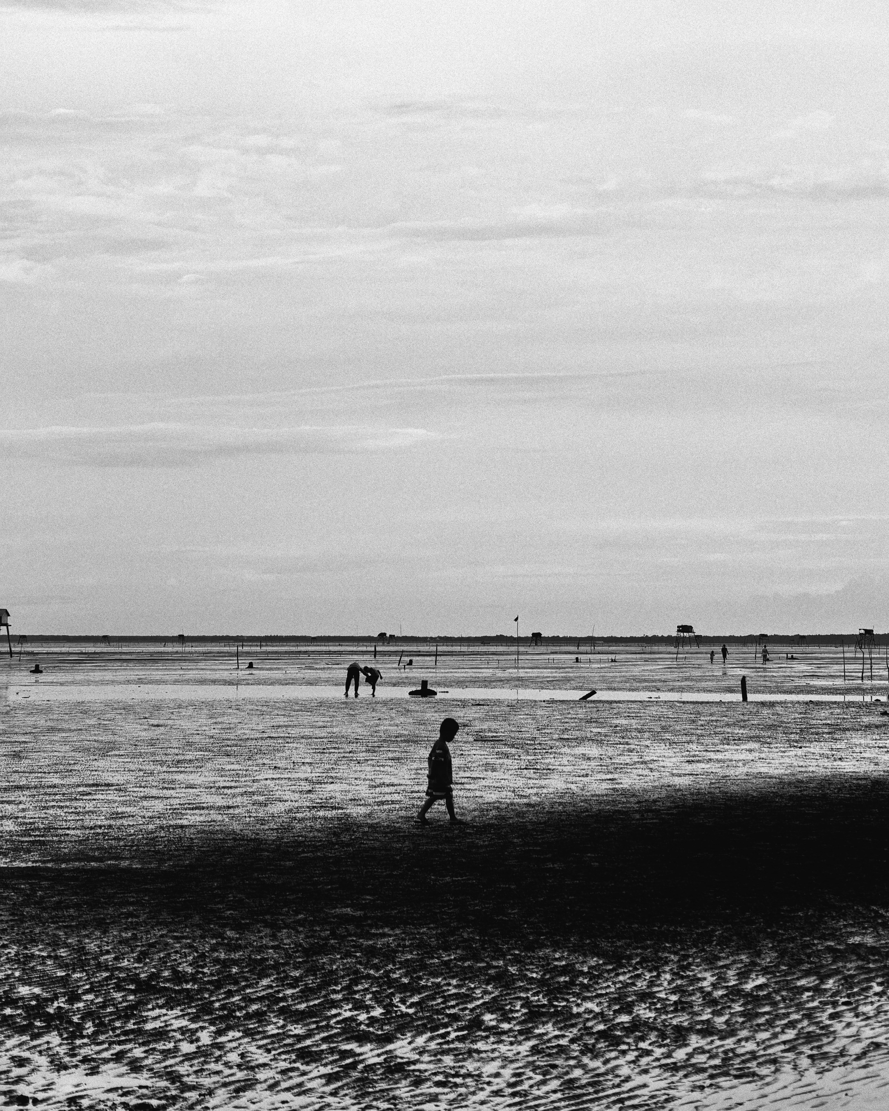 Seorang anak sendirian berjalan di pantai berpasir basah.