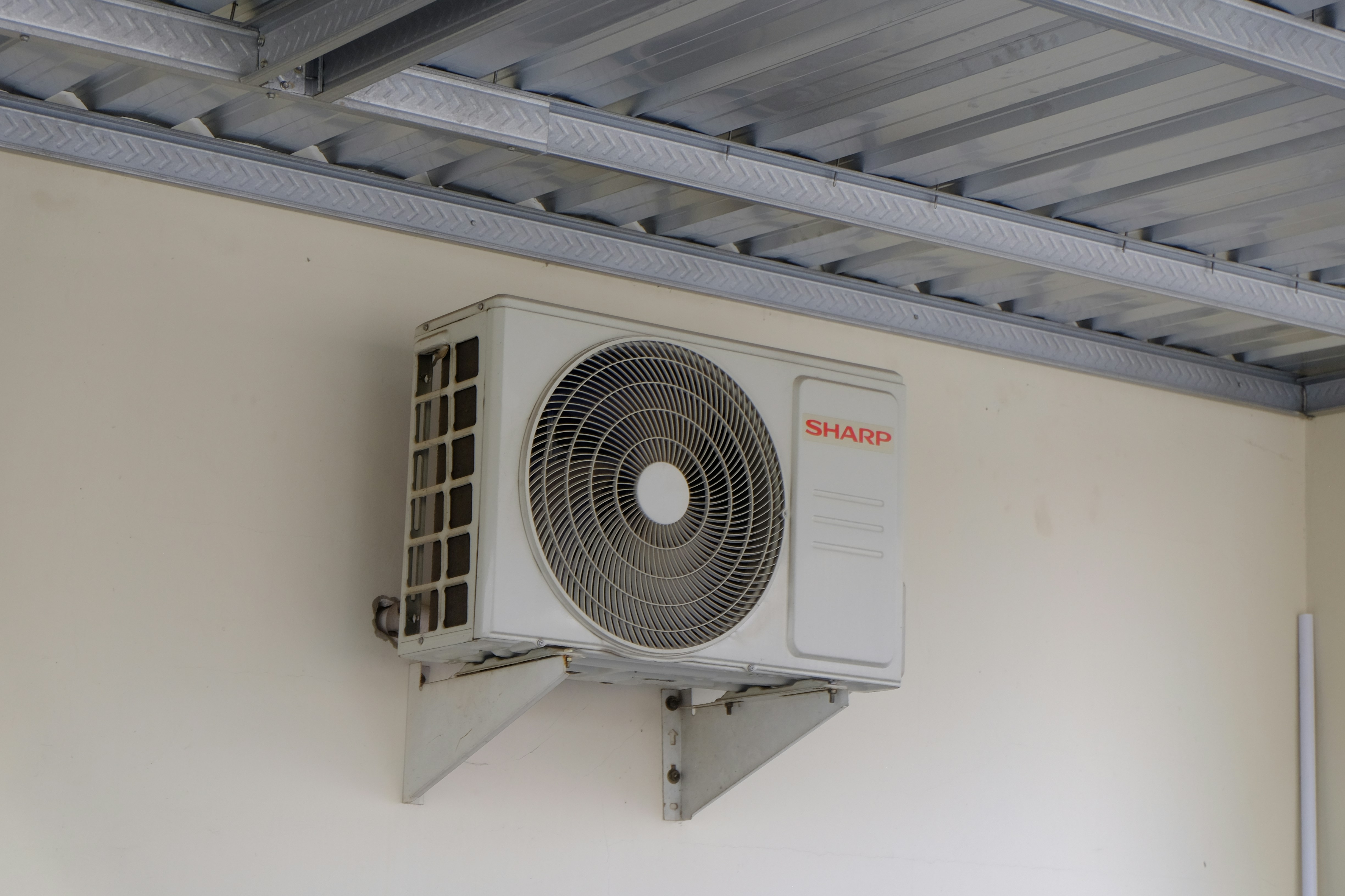 Outdoor air conditioning unit mounted on a wall, part of a home cooling and ventilation system commonly used in residential and commercial buildings.