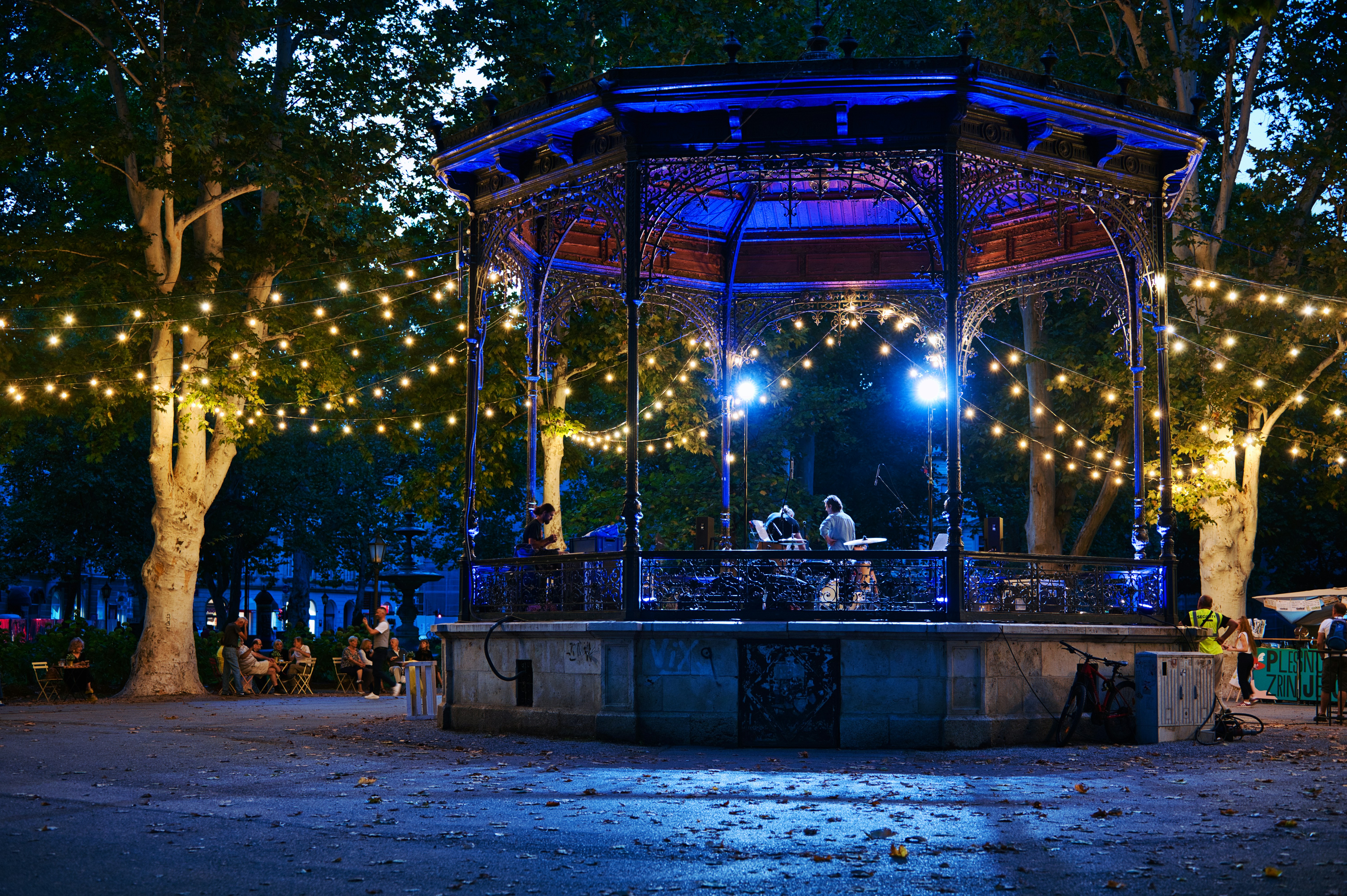Ornate bandstand illuminated with blue lights and string lights.