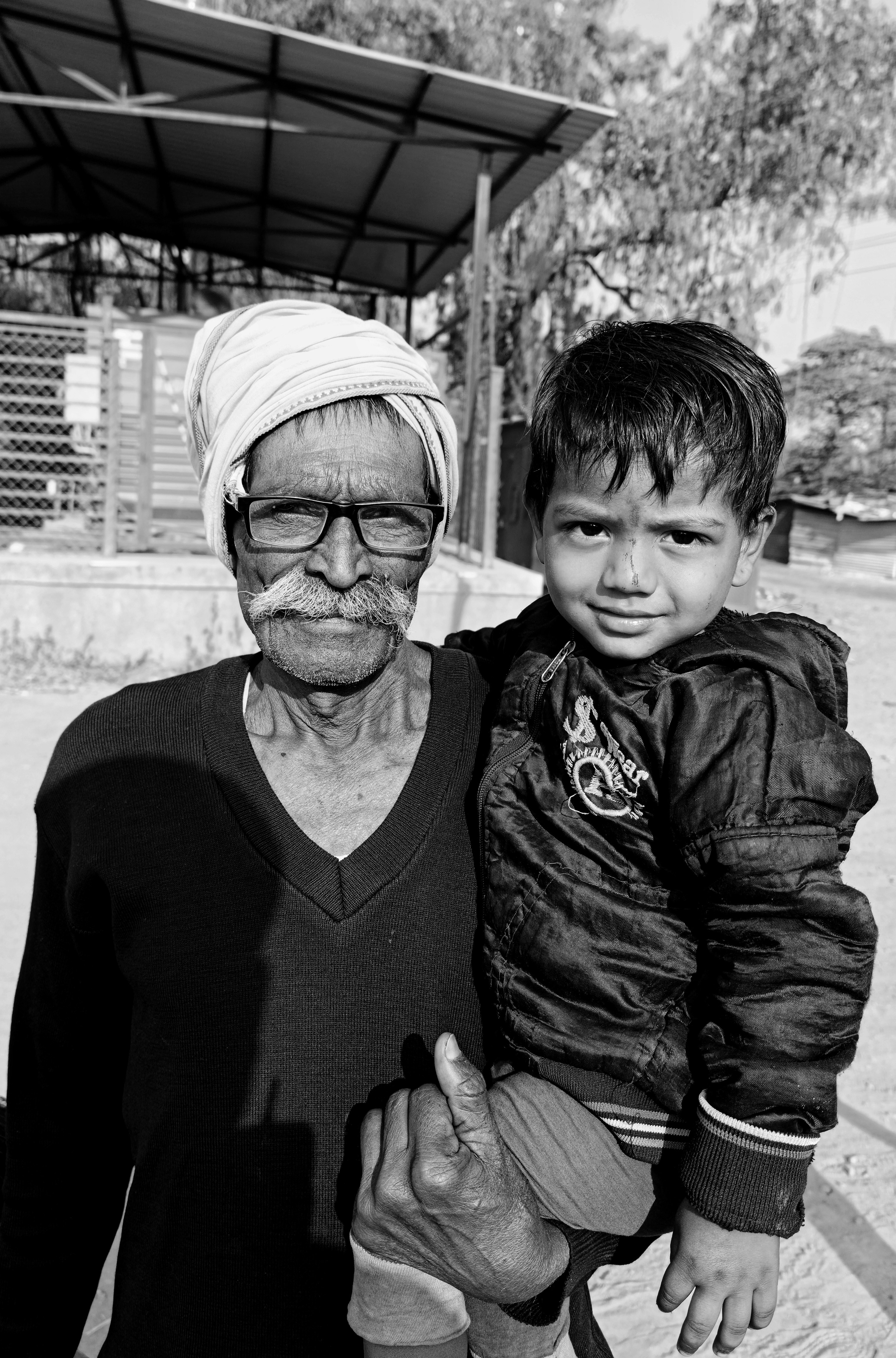 Elderly man holding a young child outdoors