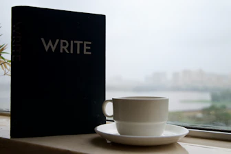 Notebook with the word write and coffee cup by window