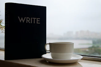 Notebook with the word write and coffee cup by window