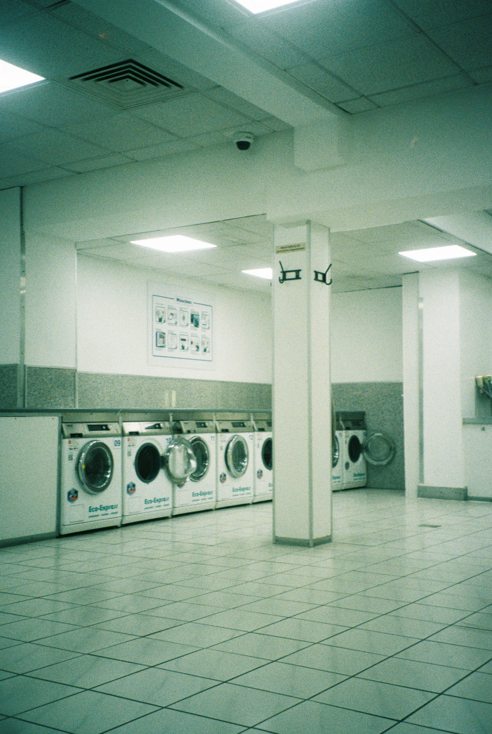 A row of washing machines in a brightly lit laundromat, the kind of space a laundry business needs to keep full