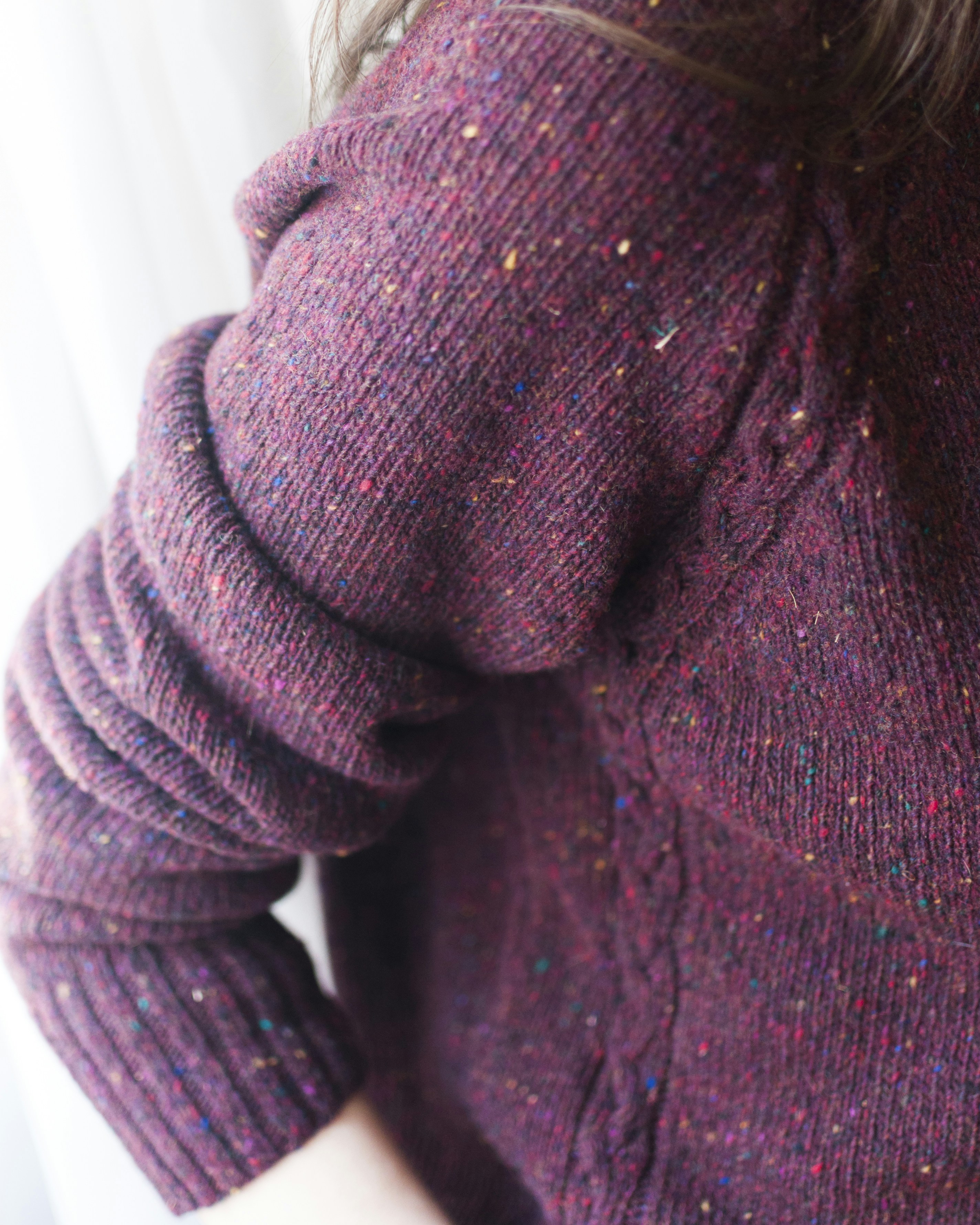 Close-up of a person wearing a textured maroon sweater.