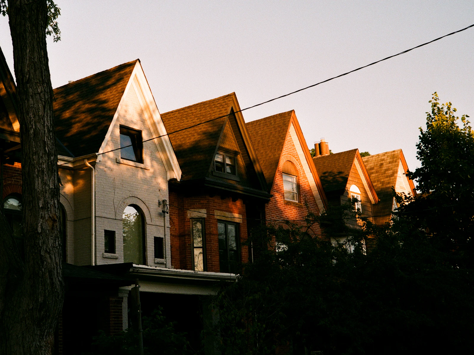 Row of brick Victorian homes glowing in warm evening light in a Toronto neighbourhood