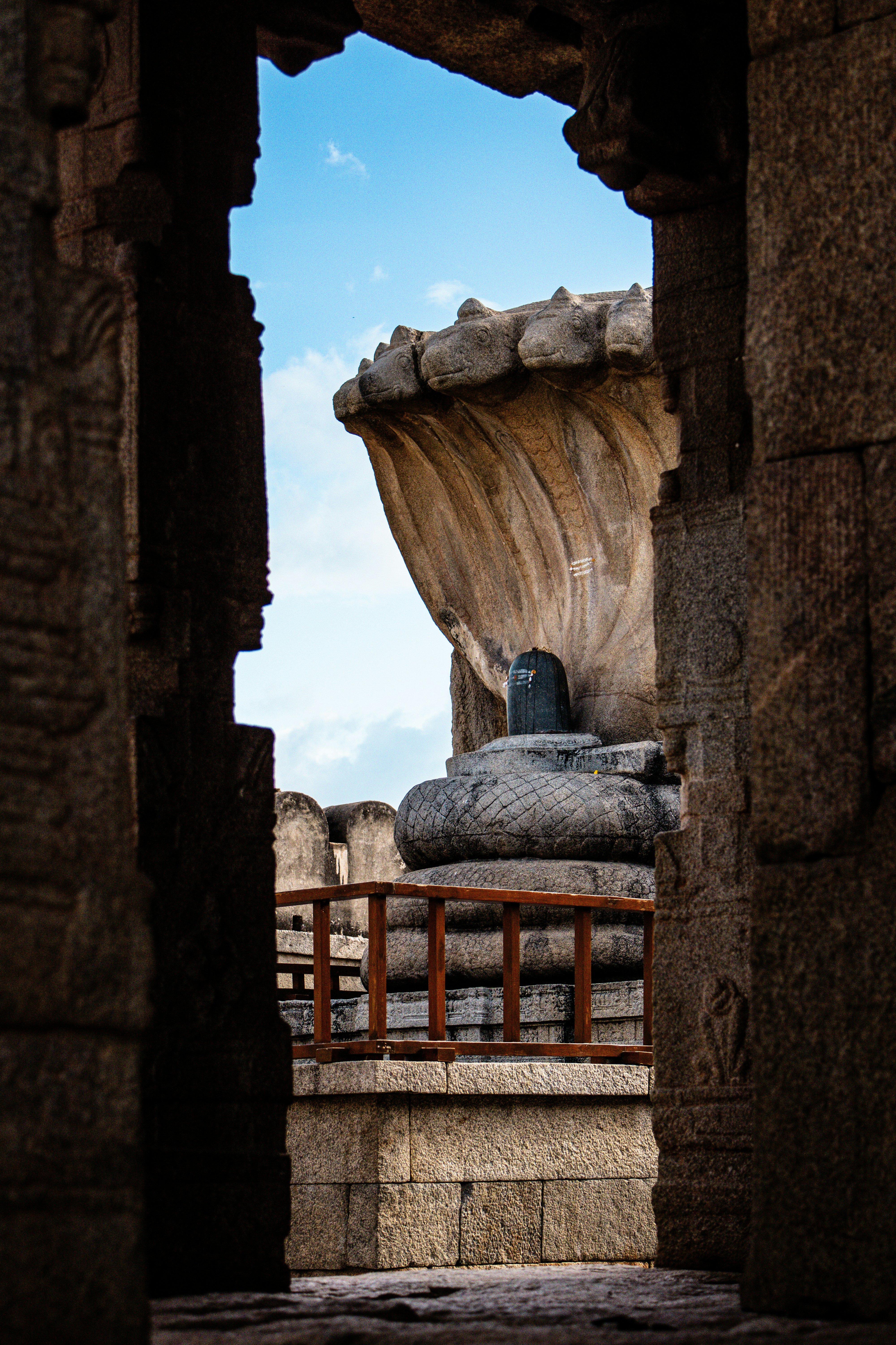 Escultura de piedra de shiva lingam bajo una capucha de serpiente.