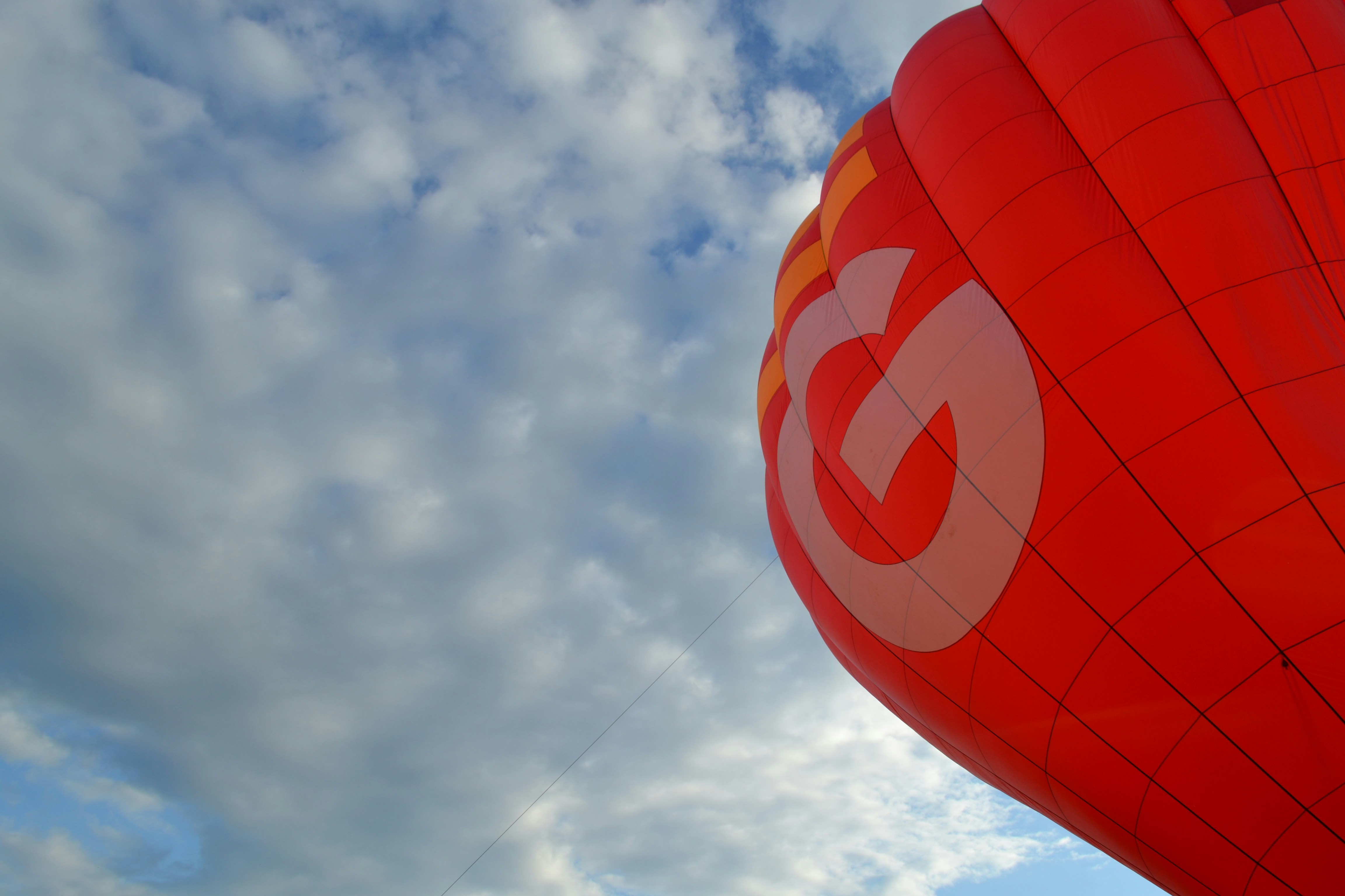 Red hot air balloon against a cloudy sky