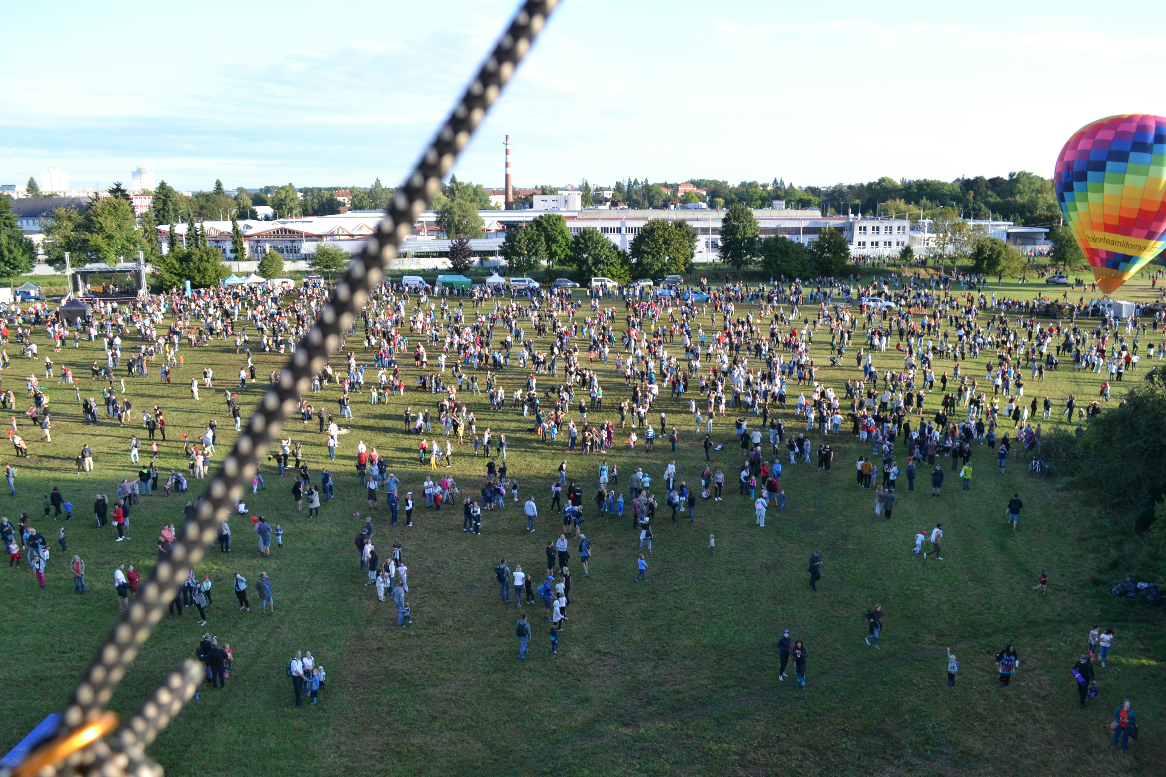 Crowd gathered in a park with a hot air balloon.