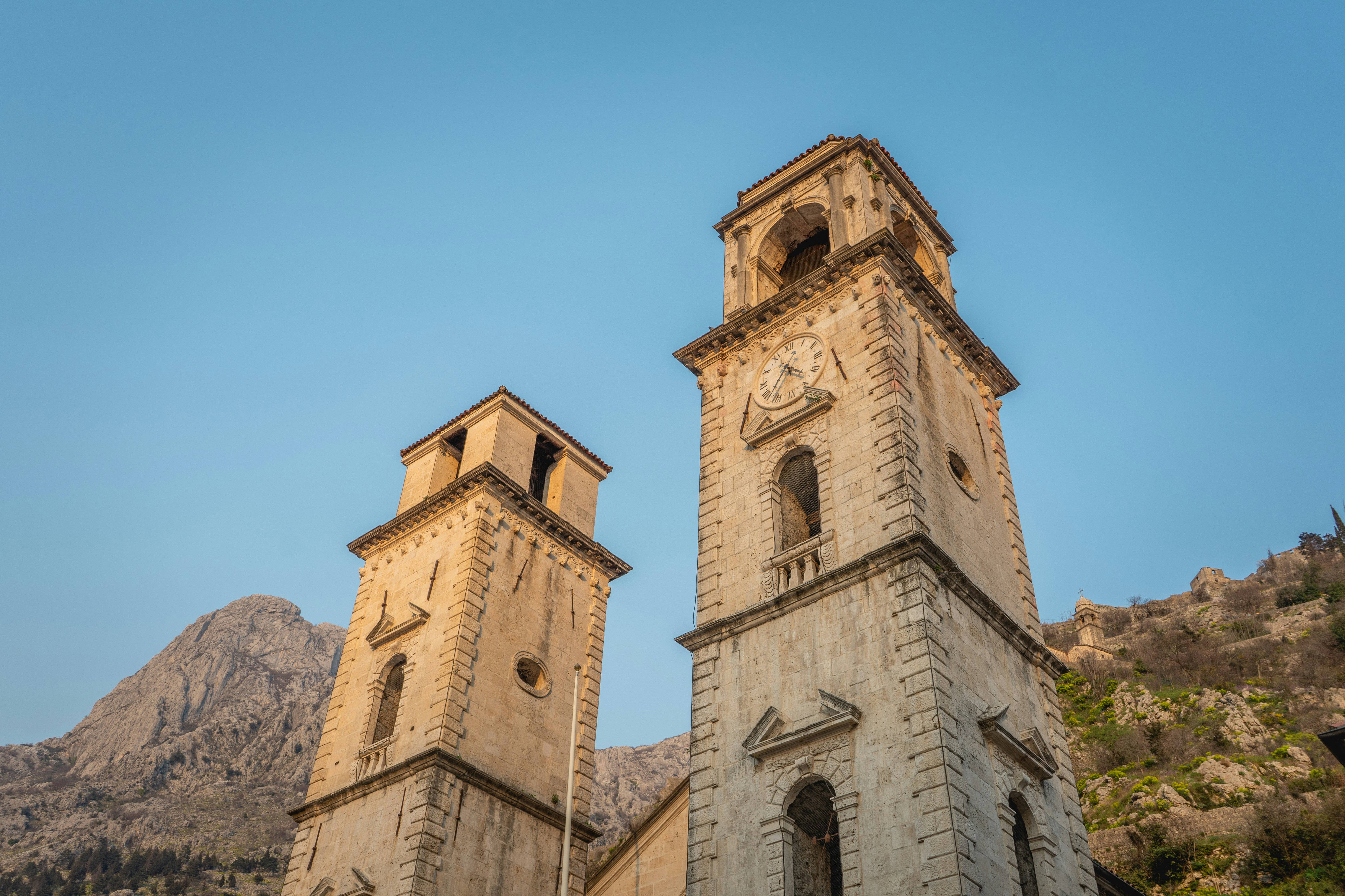 Two stone bell towers against a clear blue sky.