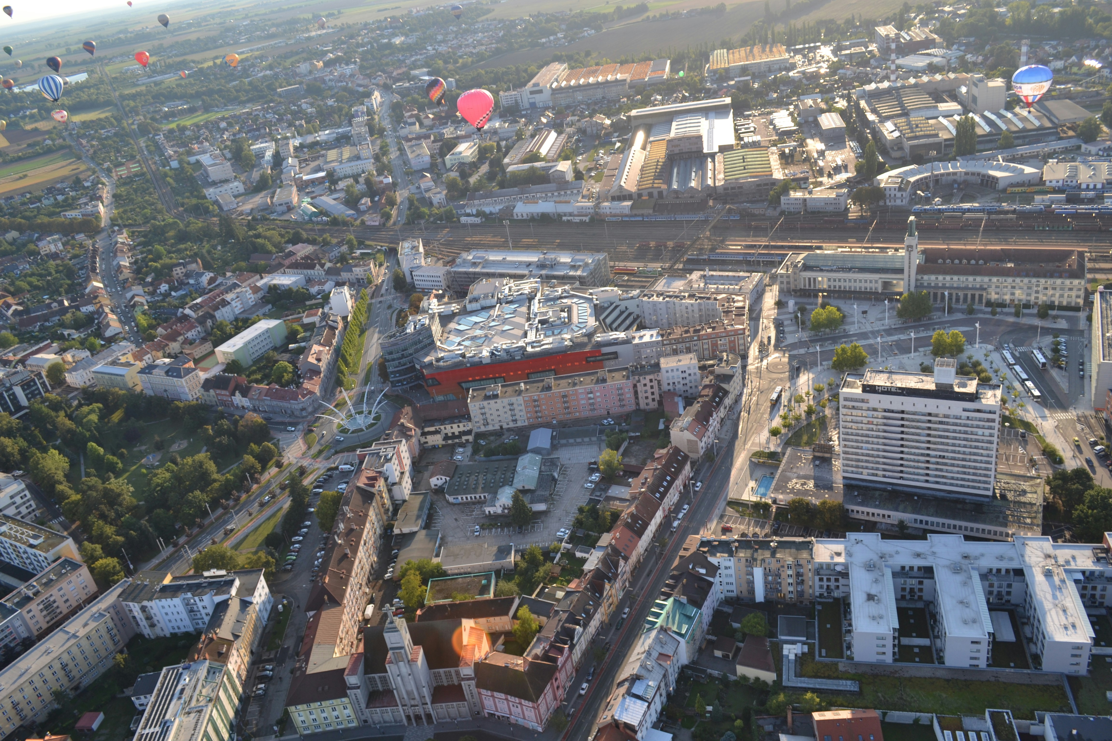 Hot air balloons flying over a city at sunrise.