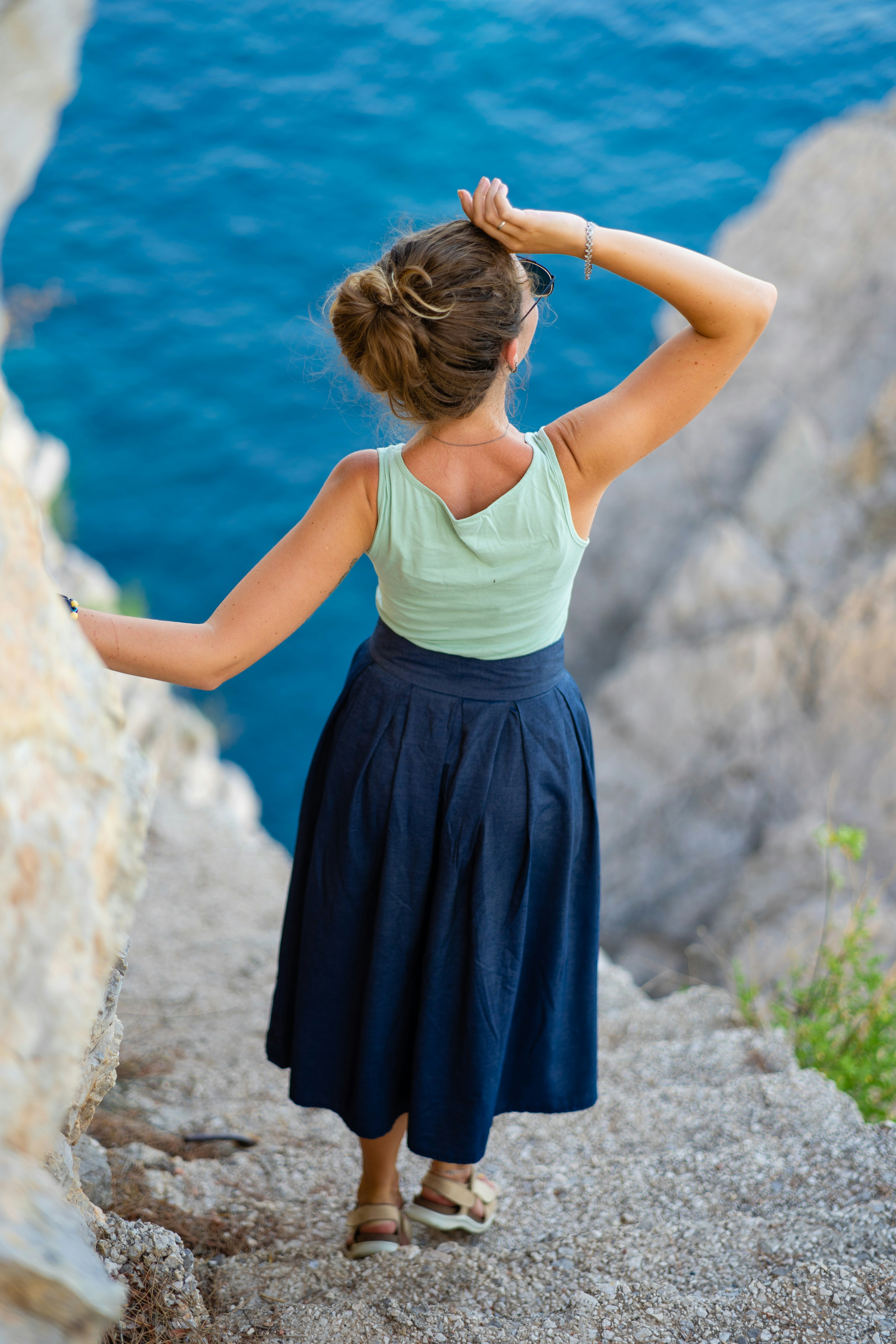 Woman on cliff overlooking blue ocean