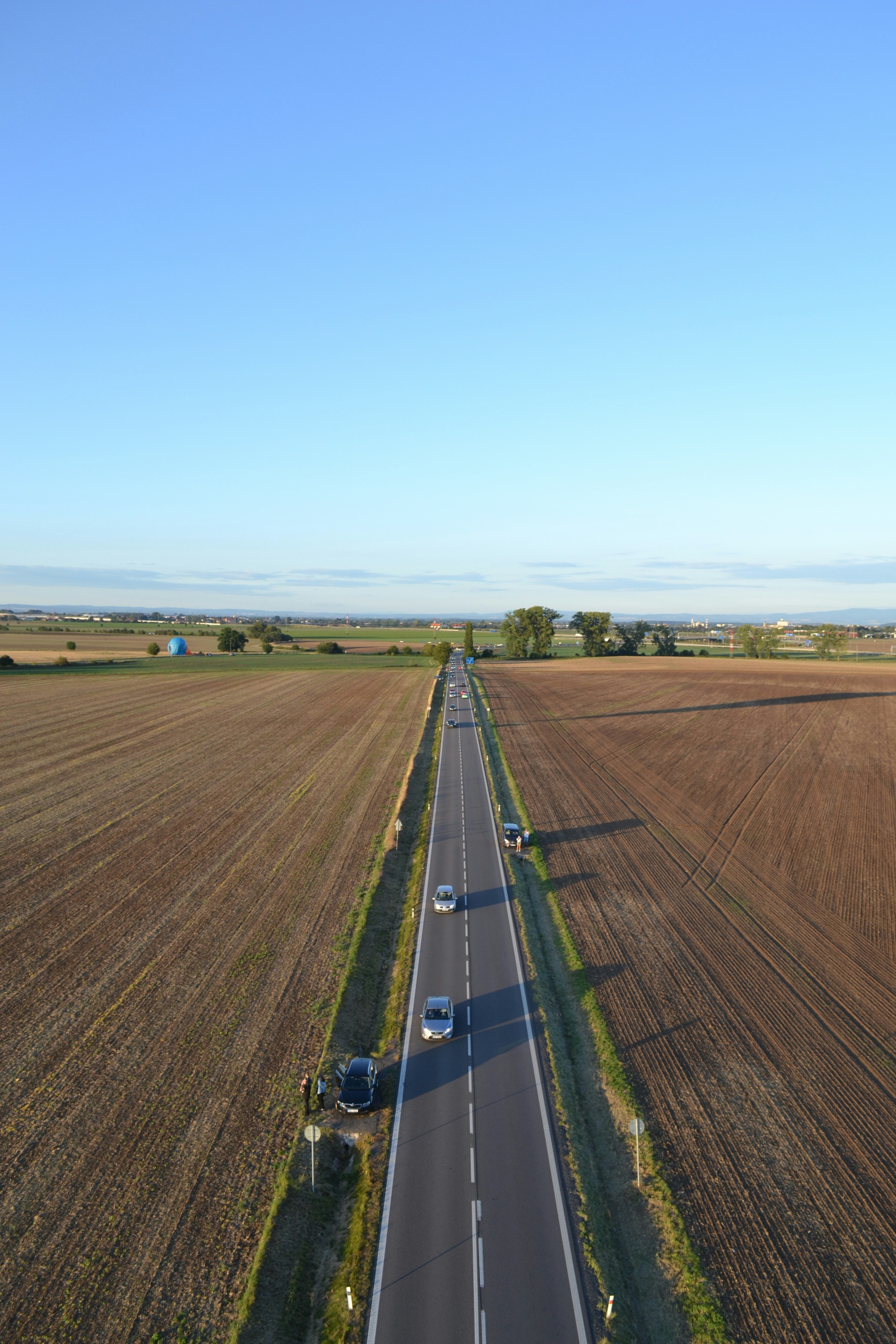 Cars driving on a straight road through farmland