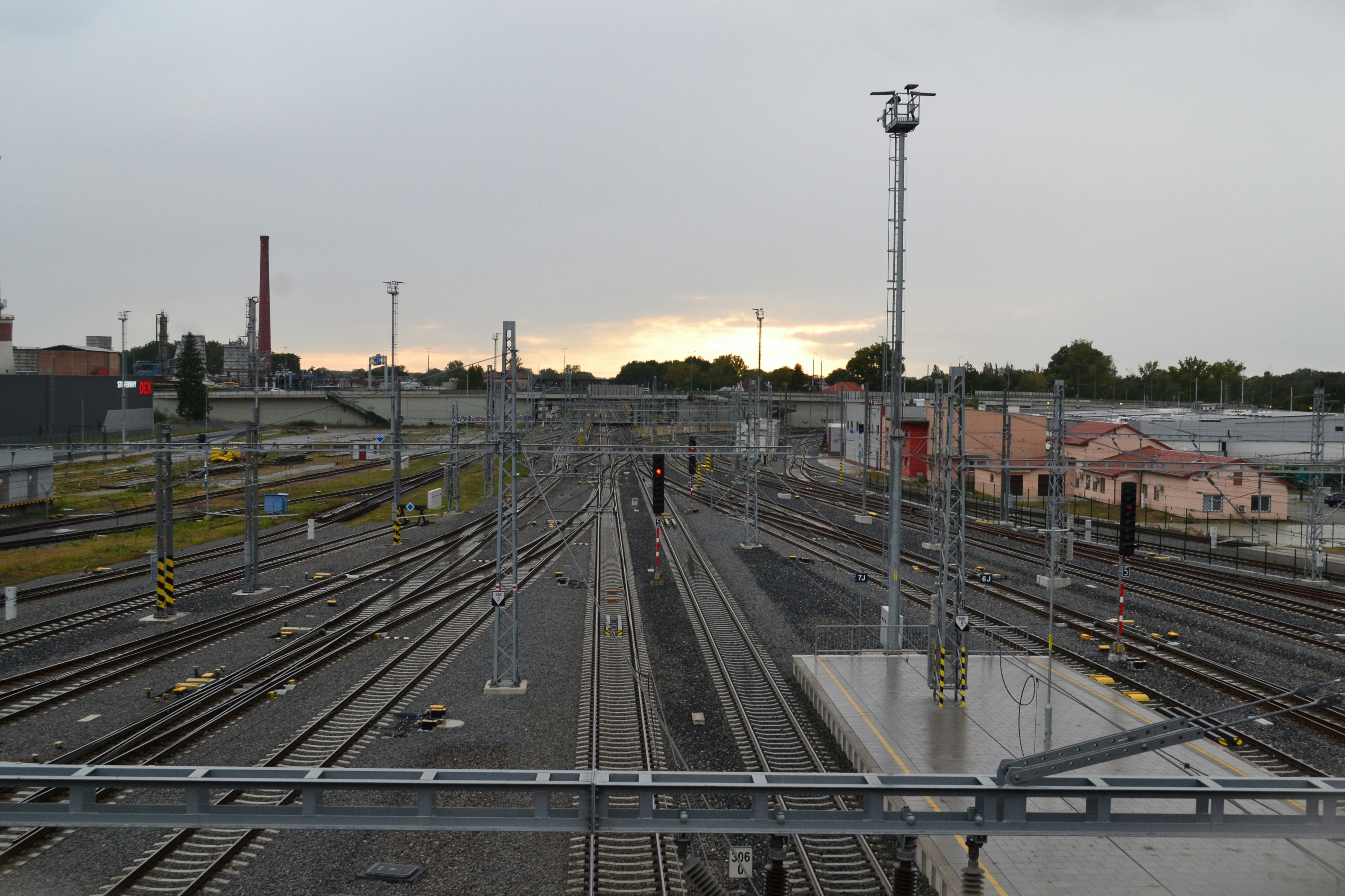 Construction workers in safety gear diligently working on a modernizing railway platform, with steel structures and new paving visible.