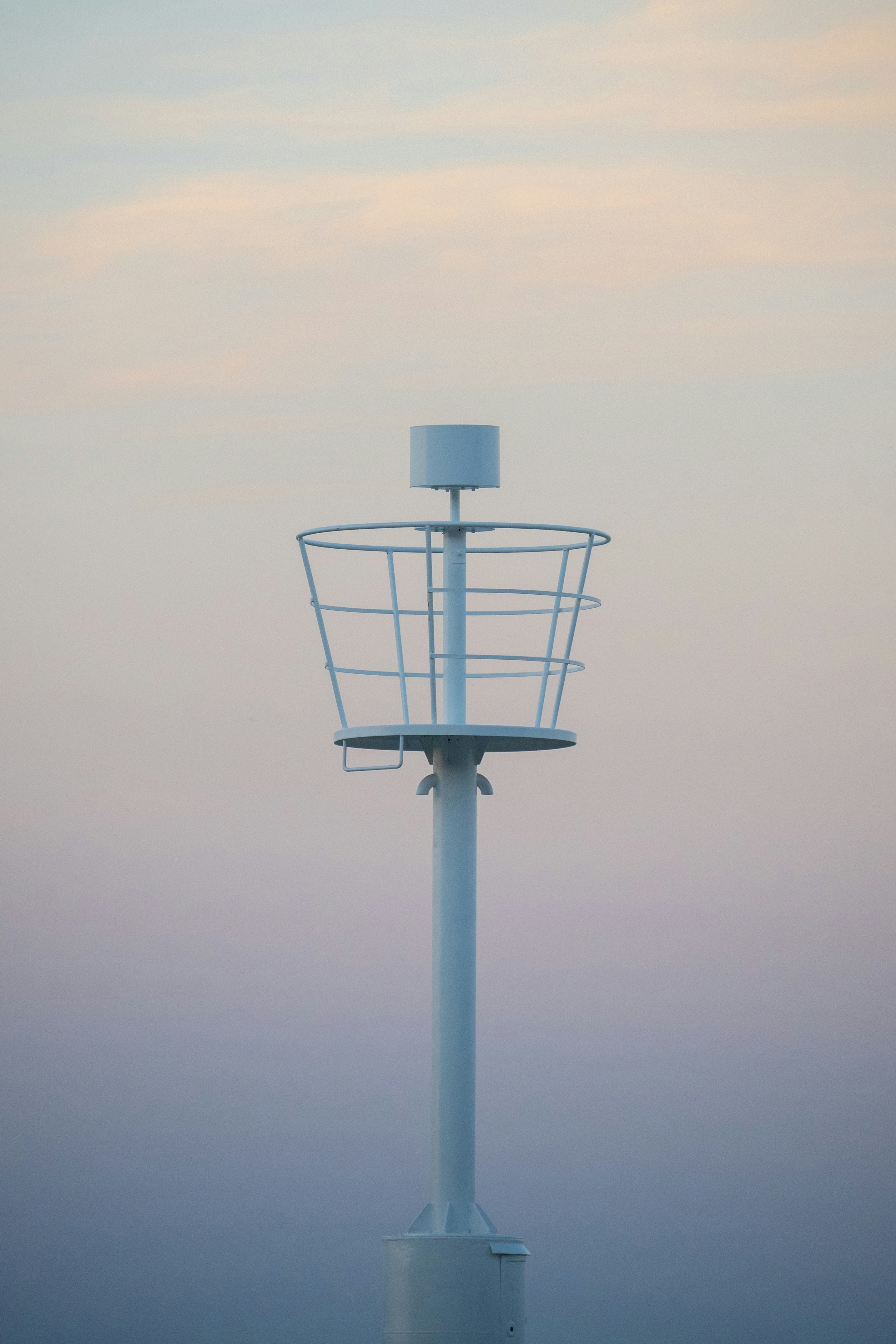Marcador de navegación blanco contra un suave cielo pastel.