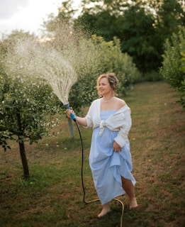 Woman watering plants with a hose in a garden