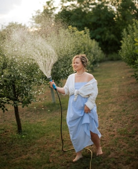 Woman watering plants with a hose in a garden