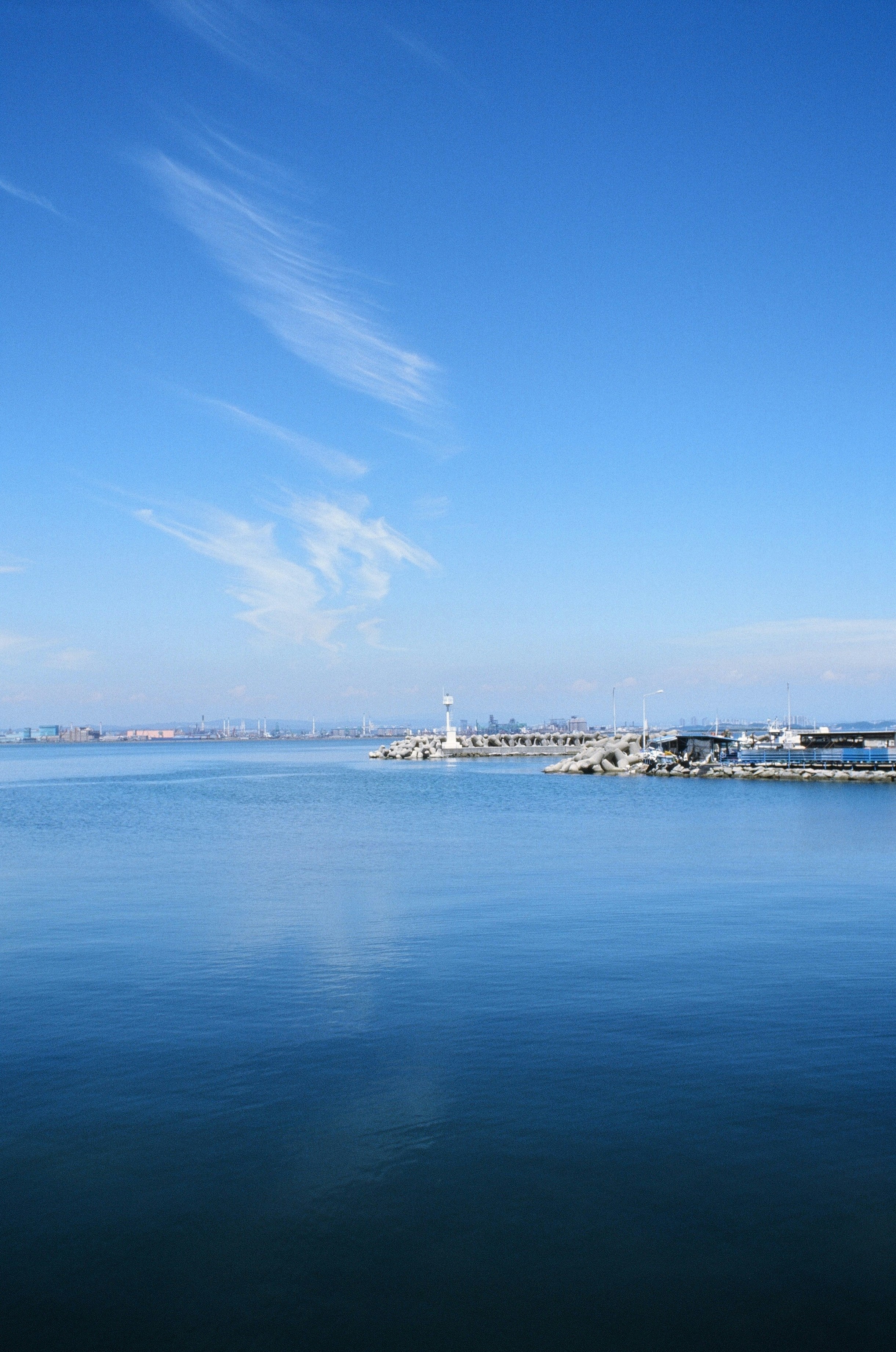 Calm blue sea with a distant lighthouse and coastline.