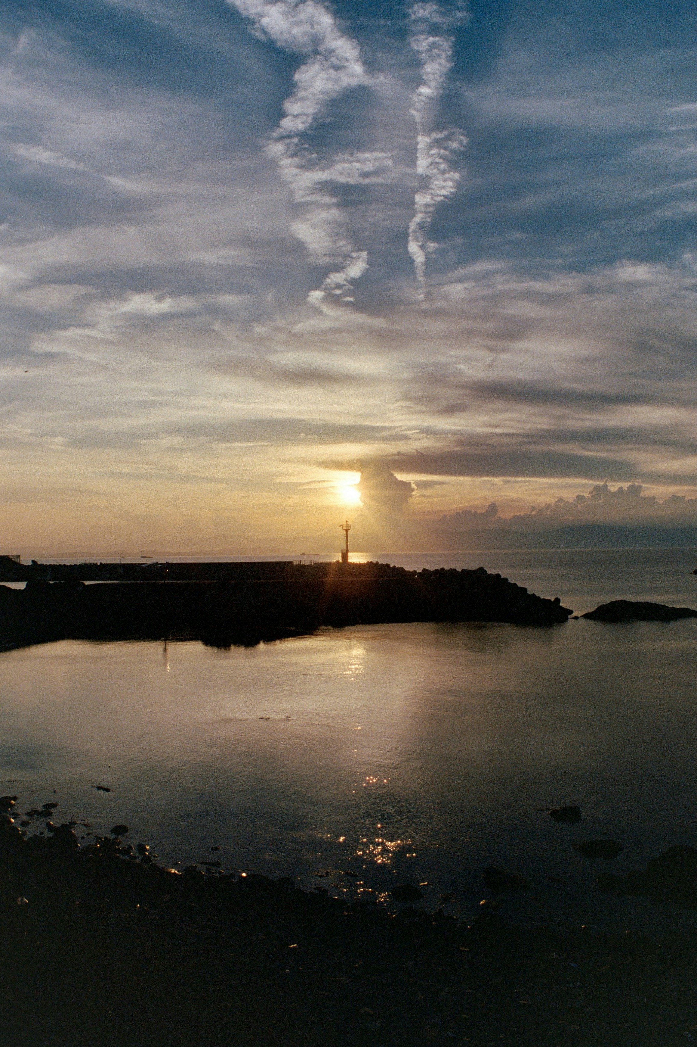 Lighthouse silhouetted against a dramatic sunset sky.