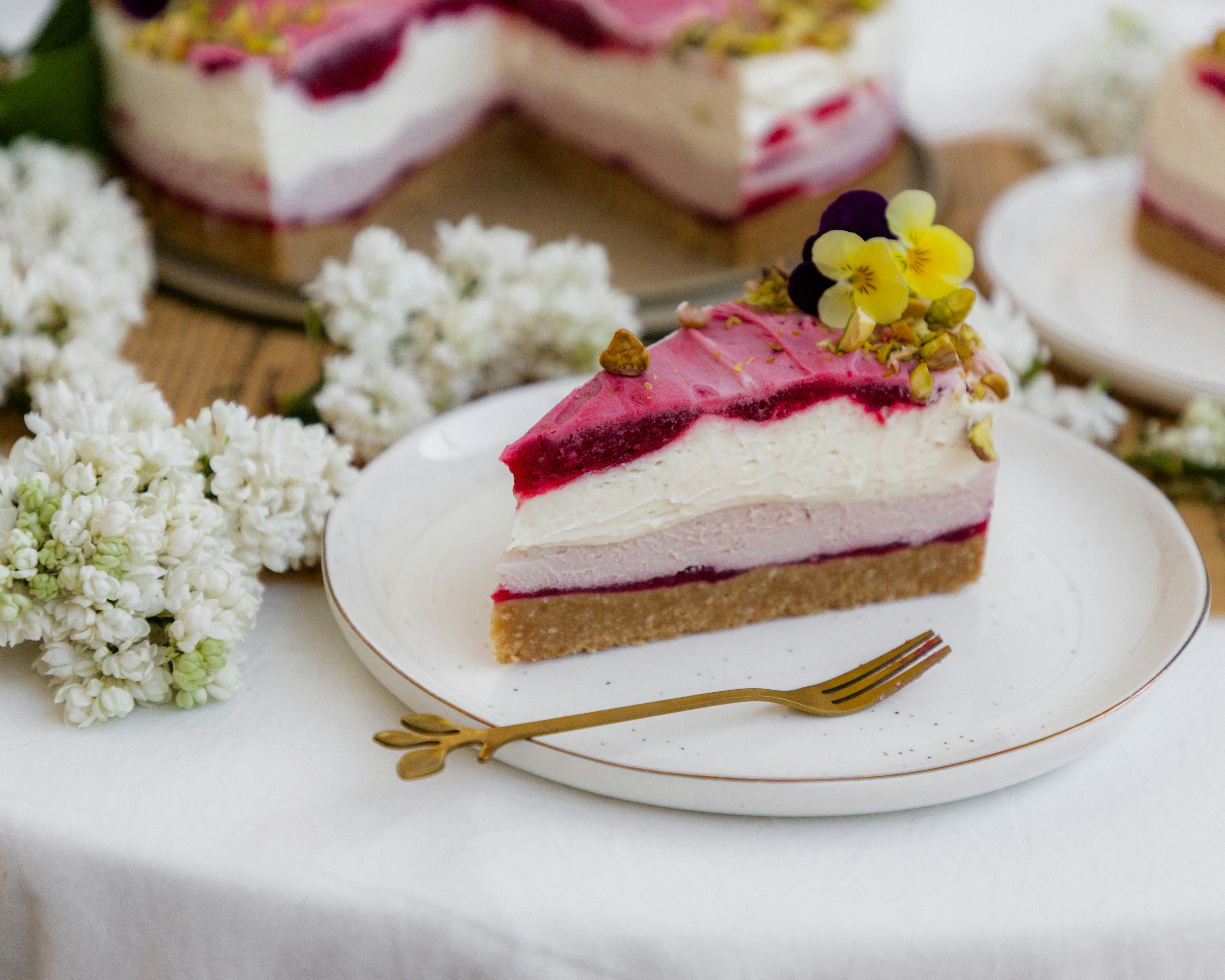 A slice of layered berry cheesecake with edible flowers photo – Free ...