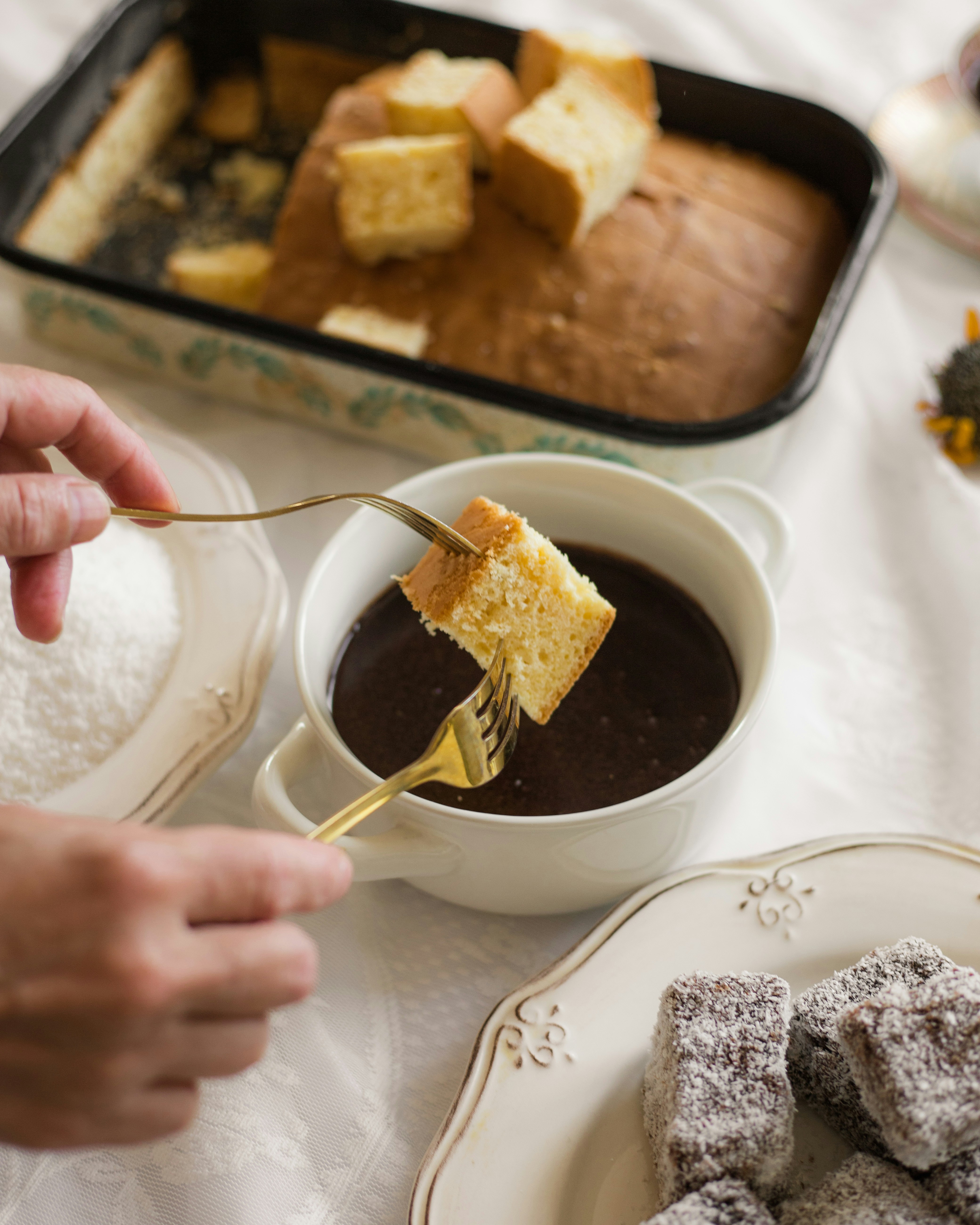 La persona immerge la torta nella salsa al cioccolato con le forchette.