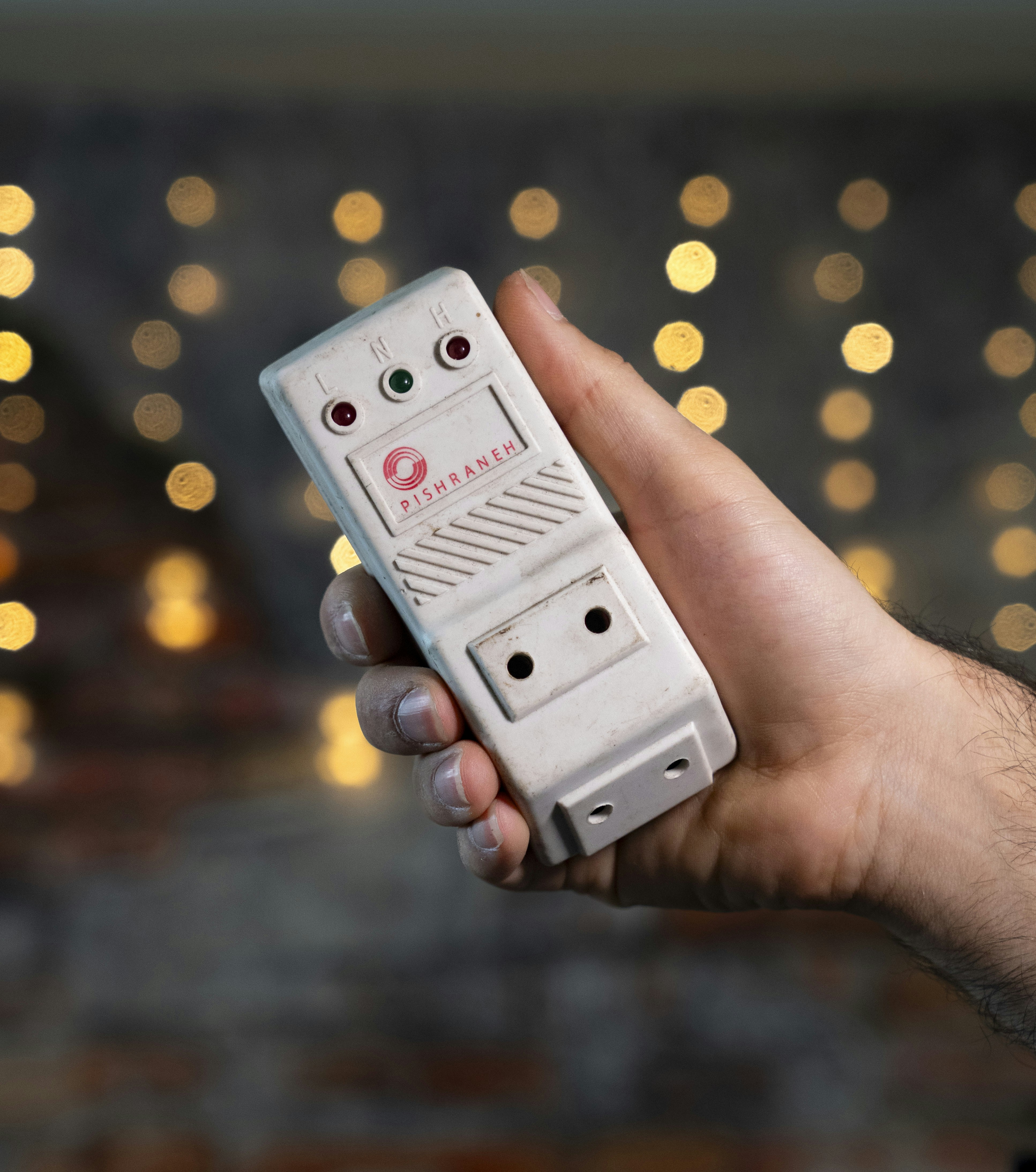 Hand holding a white electronic device with ports.