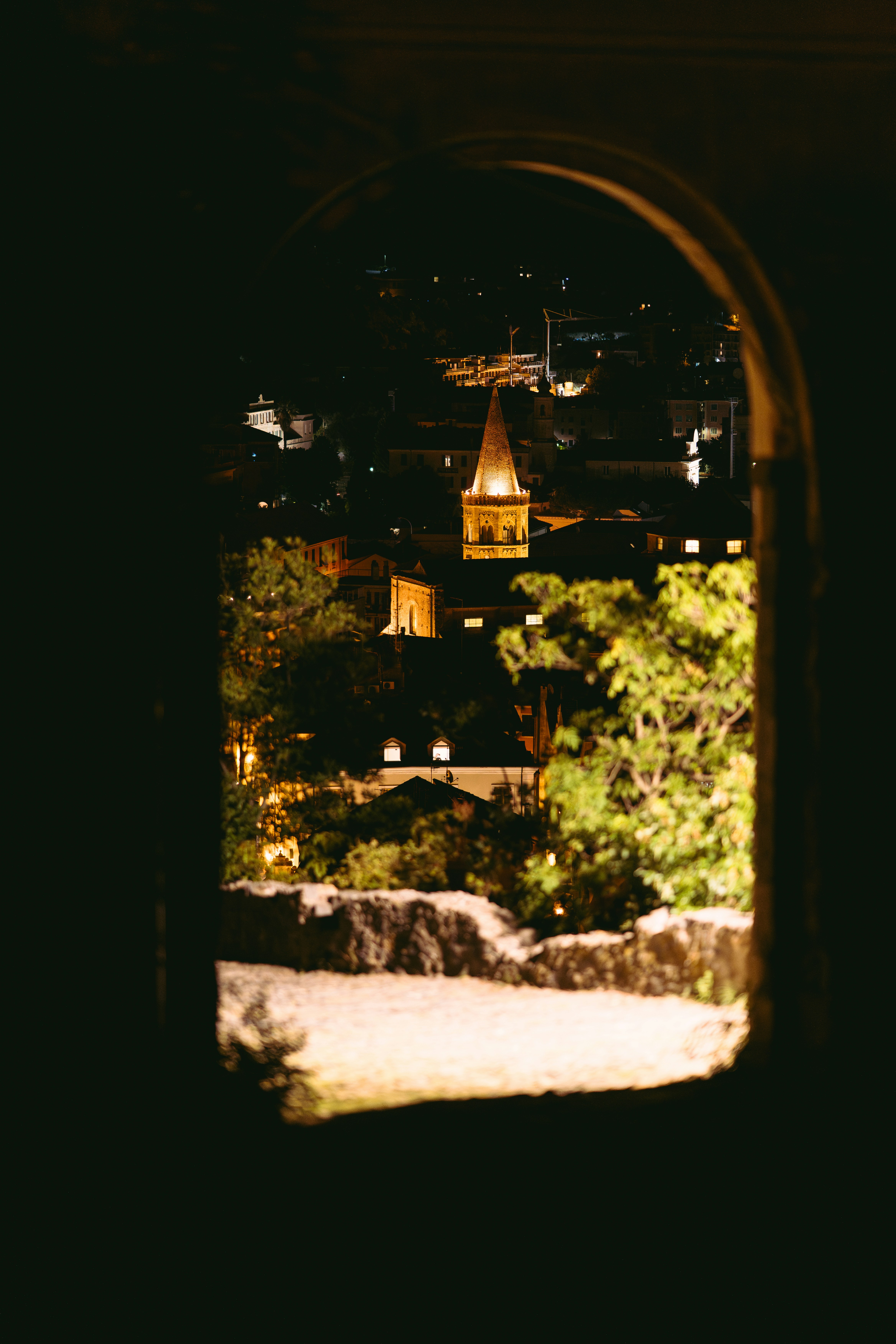 View of a town at night through an arched window.