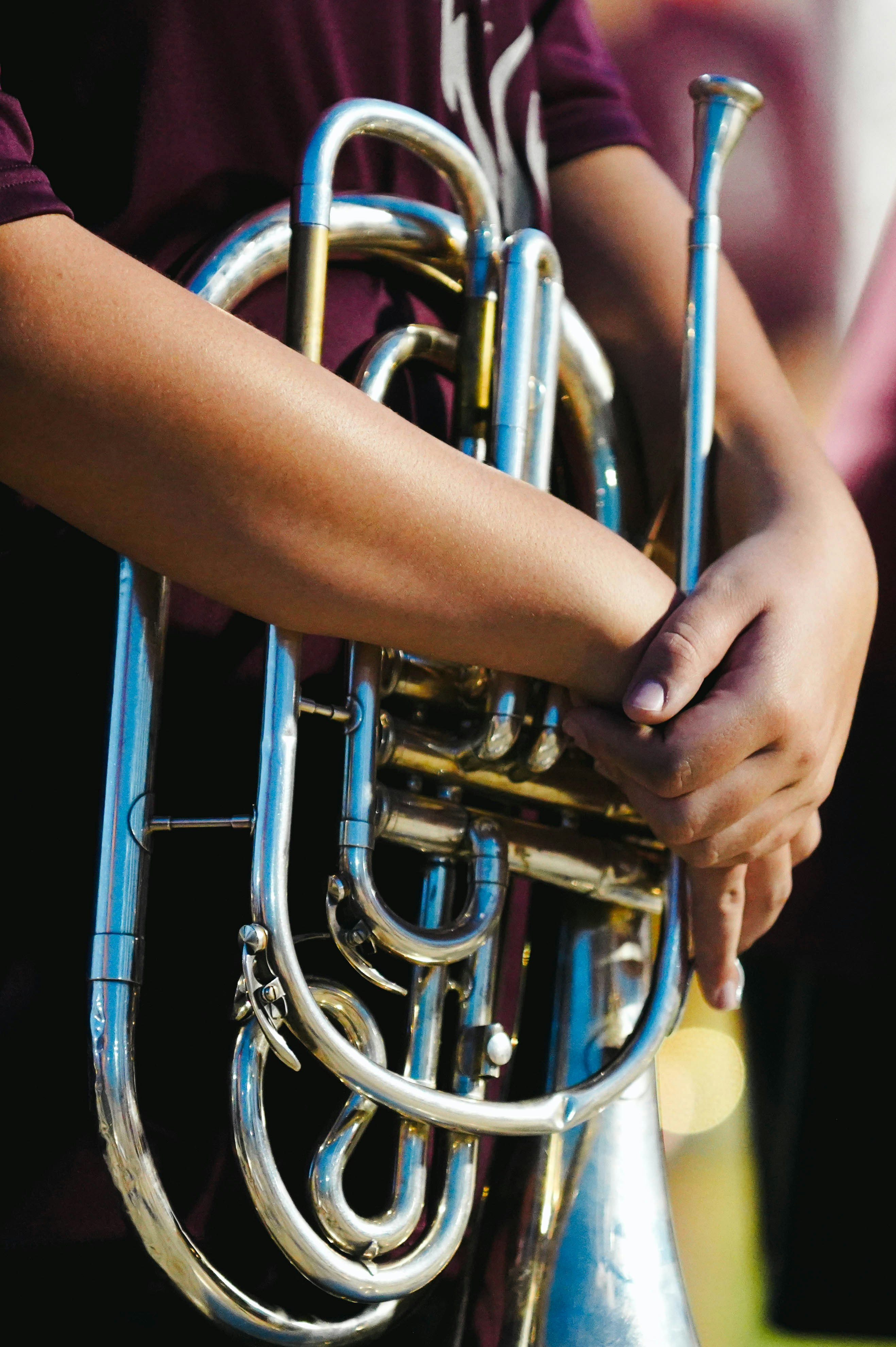 Person holding a shiny brass marching band instrument.
