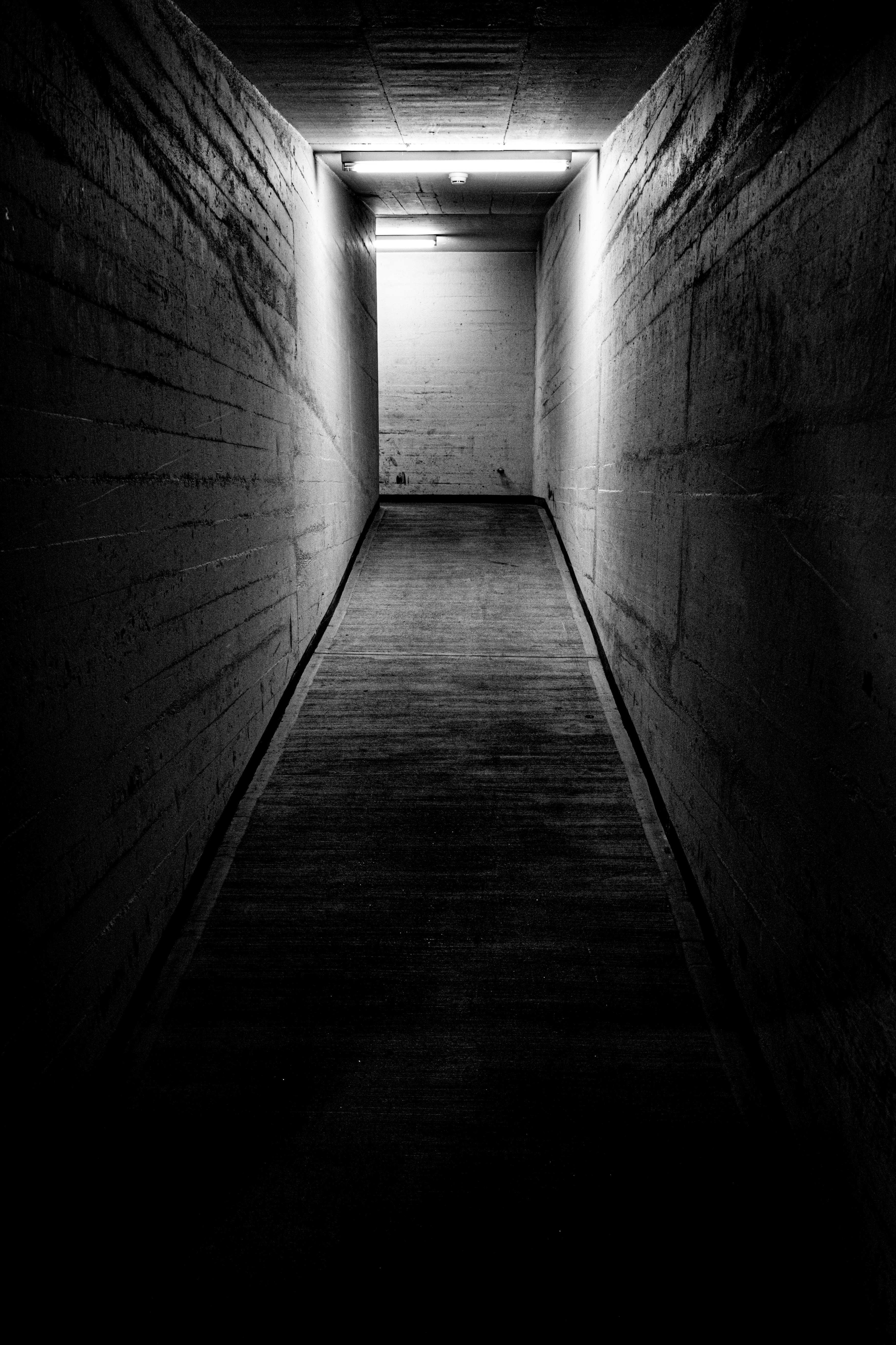 A dark concrete hallway with light at the end